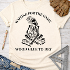 Women's funny woodworking graphic tee shirt for female woodworkers, makers, and DIY builders — Sawdust & Ponytails. Cream t-shirt with a skeleton impatiently waiting for wood glue to dry.