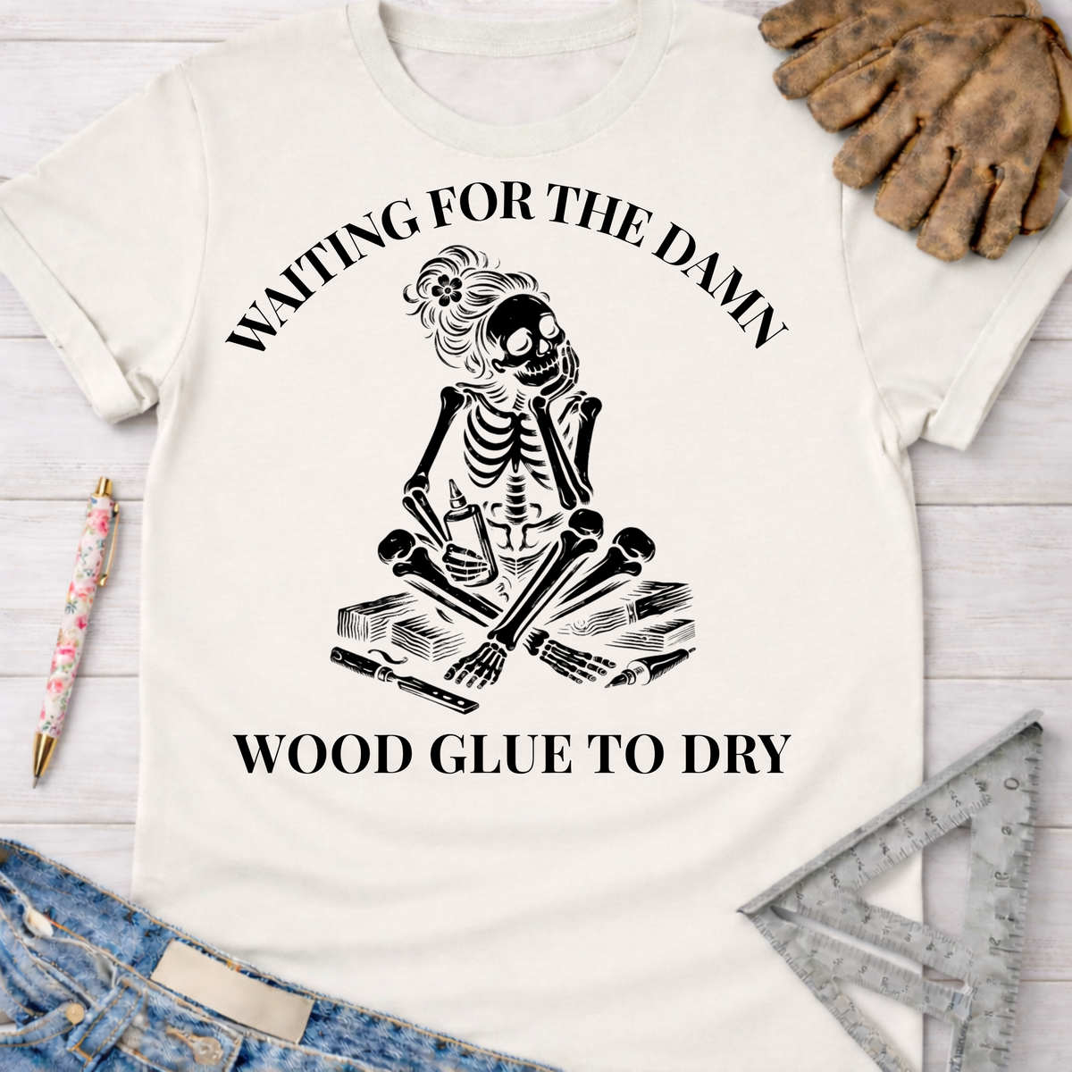 Women's funny woodworking graphic tee shirt for female woodworkers, makers, and DIY builders — Sawdust & Ponytails. White cotton t-shirt with a black skeleton graphic impatiently waiting for wood glue to dry.