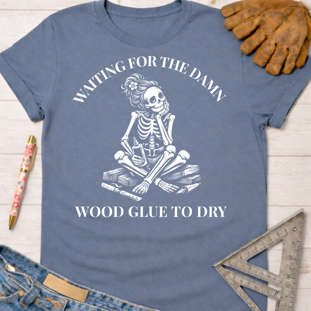 Women's funny woodworking graphic tee shirt for female woodworkers, makers, and DIY builders — Sawdust & Ponytails. Blue cotton t-shirt with a white graphic of a skeleton impatiently waiting for wood glue to dry.