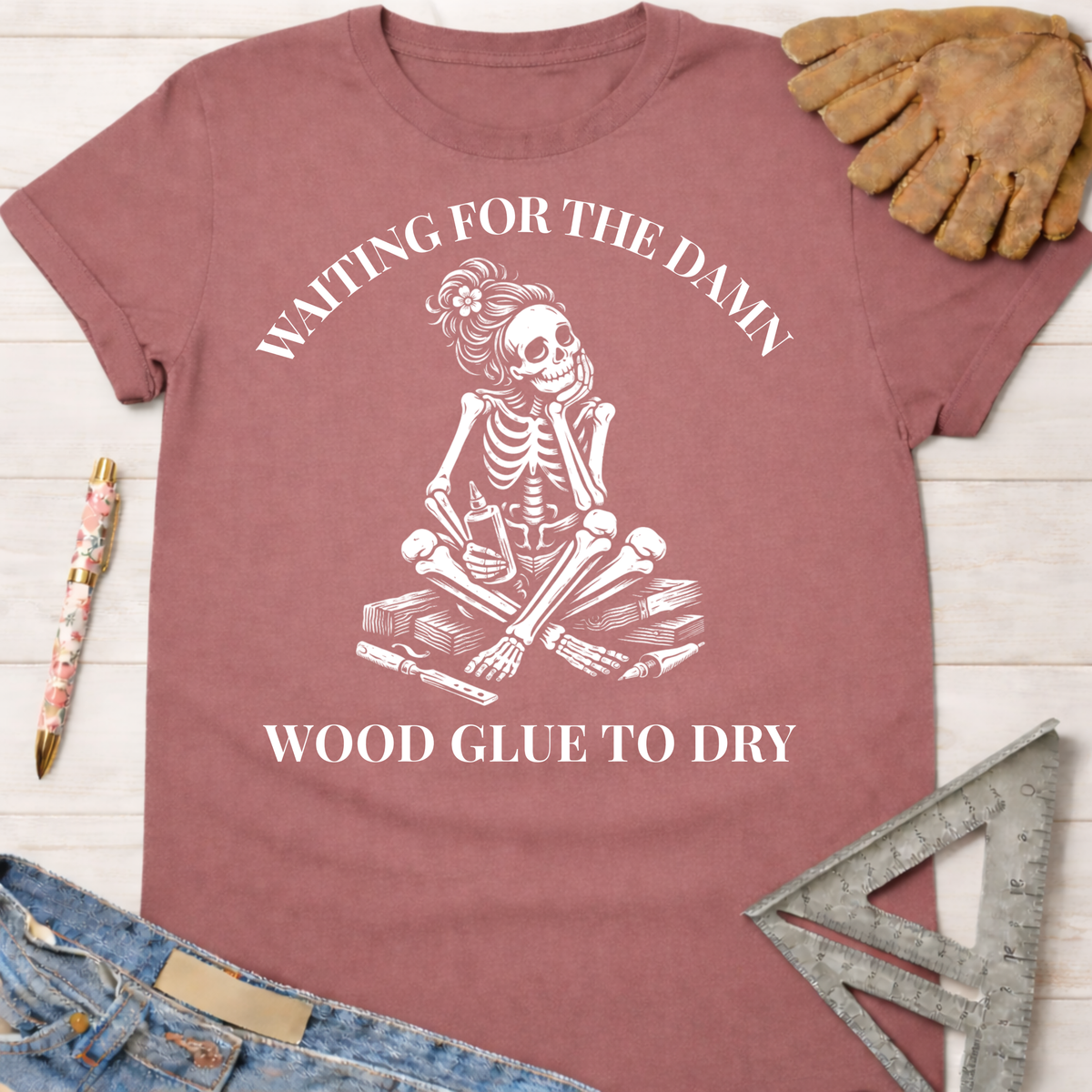 Women's funny woodworking graphic tee shirt for female woodworkers, makers, and DIY builders — Sawdust & Ponytails. Mauve cotton t-shirt with a skeleton impatiently waiting for wood glue to dry.