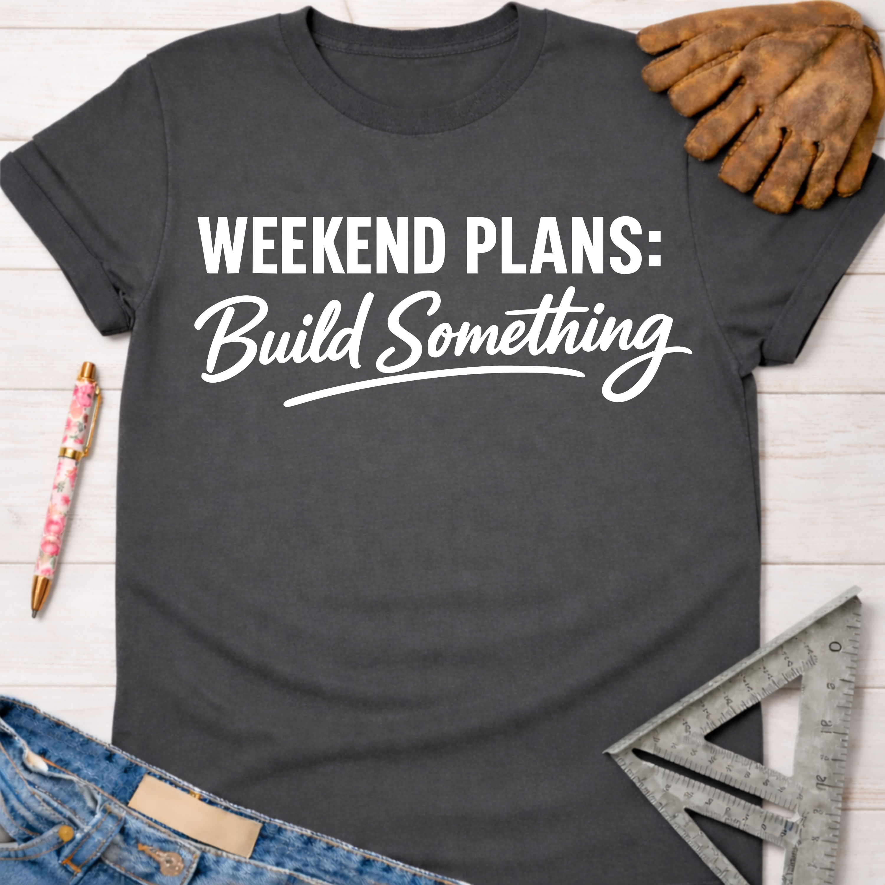 Women's funny woodworking graphic tee shirt for female woodworkers, makers, and DIY builders — Sawdust & Ponytails. Dark gray cotton tee with "Weekend Plans: Build Something" in white text, styled with jeans, pen, and tools.