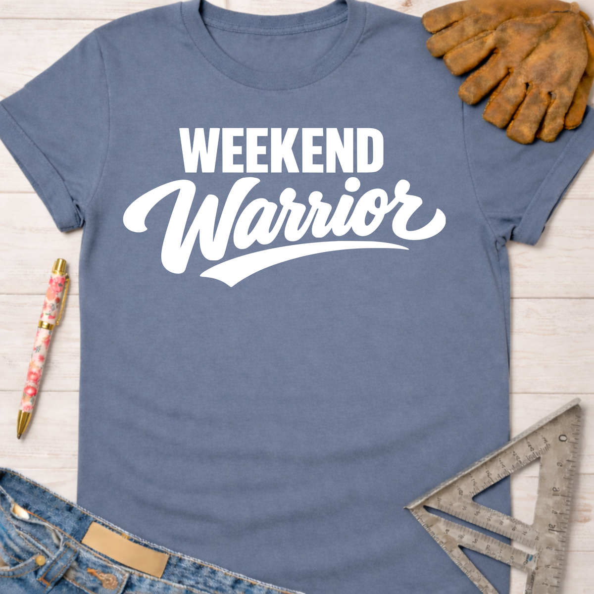 Women's funny woodworking graphic tee shirt for female woodworkers, makers, and DIY builders — Sawdust & Ponytails. Blue cotton t-shirt with "Weekend Warrior" in white text, next to work gloves, jeans, and a ruler.
