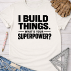Women's funny woodworking graphic tee shirt for female woodworkers, makers, and DIY builders — Sawdust & Ponytails. White cotton t-shirt with "I BUILD THINGS. WHAT'S YOUR SUPERPOWER?" in black text.