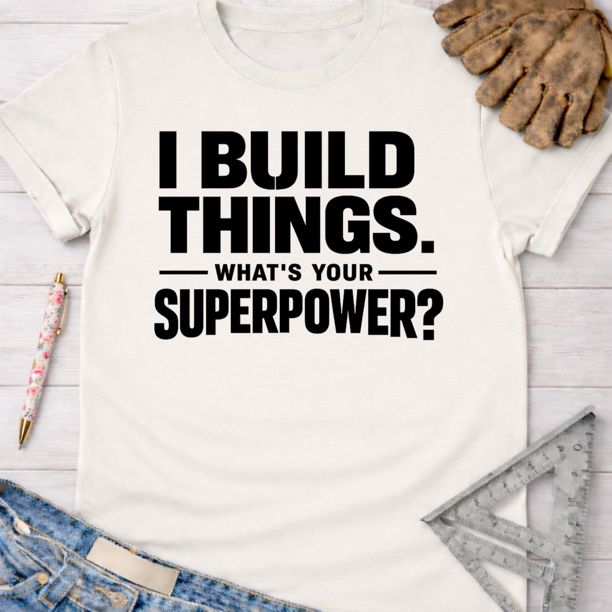 Women's funny woodworking graphic tee shirt for female woodworkers, makers, and DIY builders — Sawdust & Ponytails. White cotton t-shirt with "I BUILD THINGS. WHAT'S YOUR SUPERPOWER?" in black text.