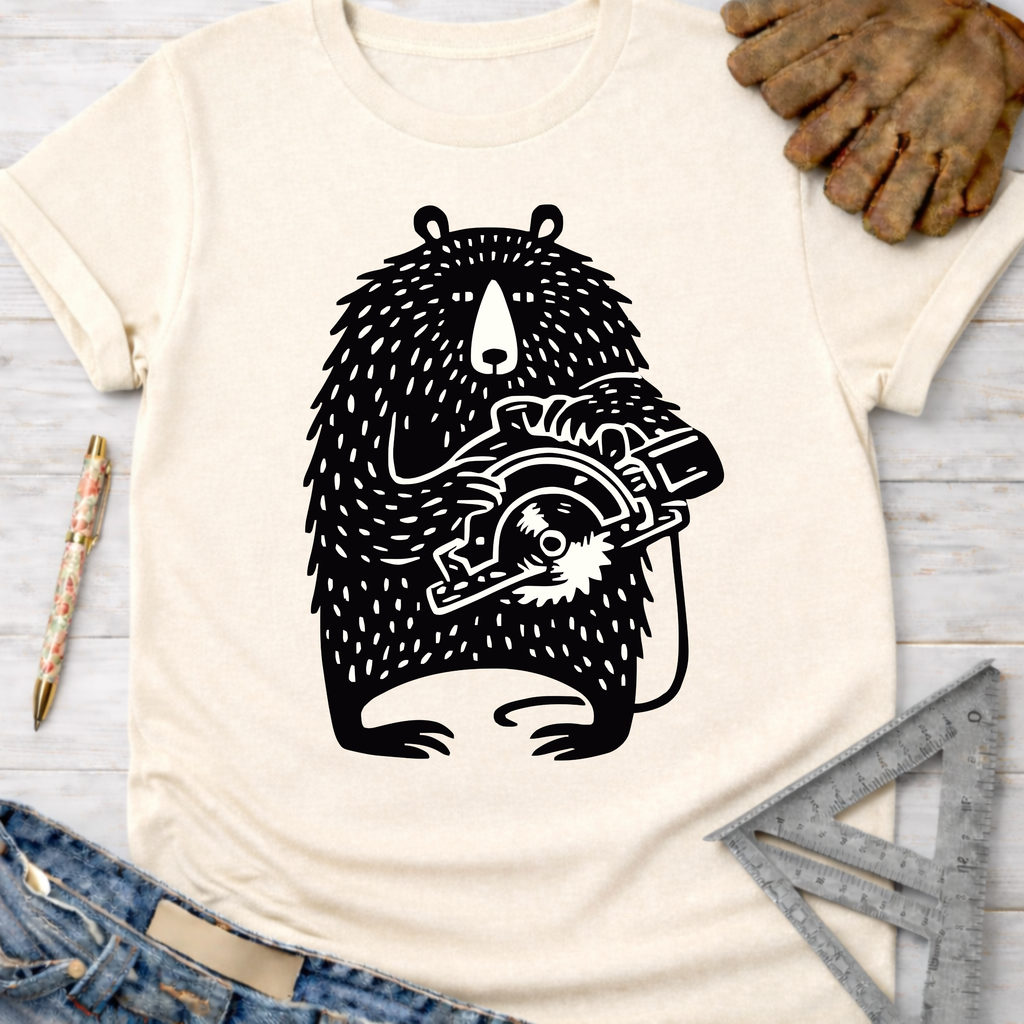 Women's funny woodworking graphic tee shirt for female woodworkers, makers, and DIY builders — Sawdust & Ponytails. Cream tee with black bear holding a circular saw.