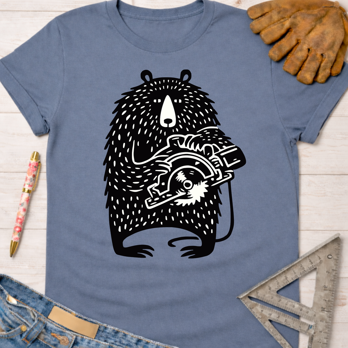 Women's funny woodworking graphic tee shirt for female woodworkers, makers, and DIY builders — Sawdust & Ponytails. Blue t-shirt with a black bear holding a circular saw graphic.