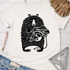 Women's funny woodworking graphic tee shirt for female woodworkers, makers, and DIY builders — Sawdust & Ponytails. White cotton tee with a black whimsical bear holding a circular saw graphic.