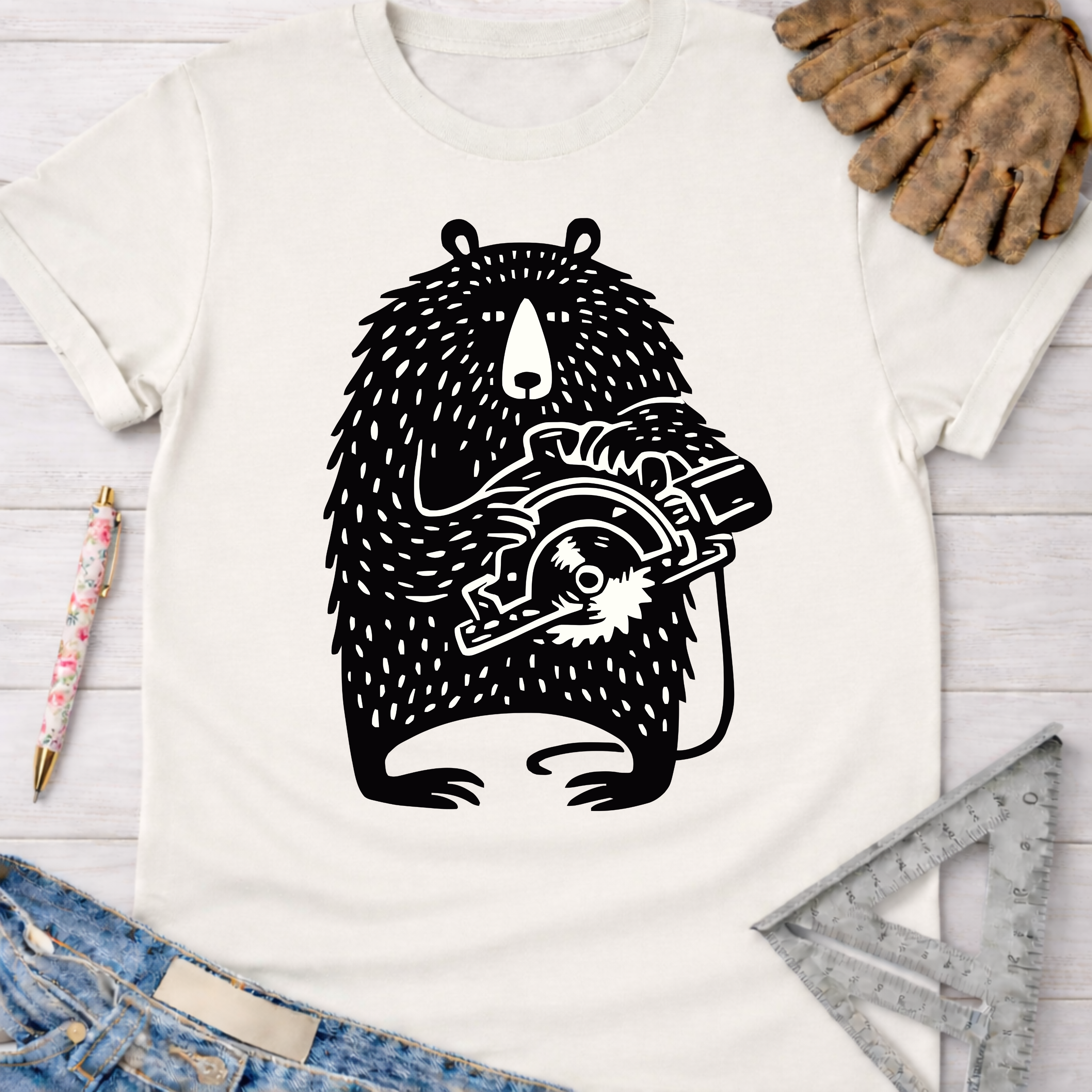 Women's funny woodworking graphic tee shirt for female woodworkers, makers, and DIY builders — Sawdust & Ponytails. White cotton tee with a black whimsical bear holding a circular saw graphic.