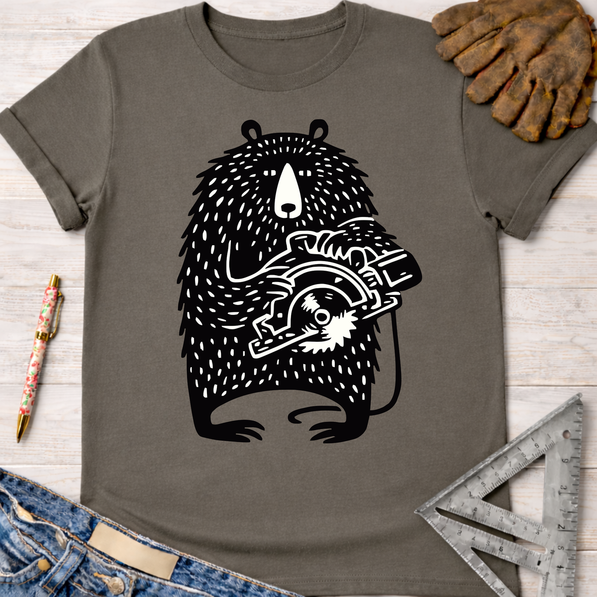 Women's funny woodworking graphic tee shirt for female woodworkers, makers, and DIY builders — Sawdust & Ponytails. Dark gray cotton tee with a black and white bear holding a circular saw.