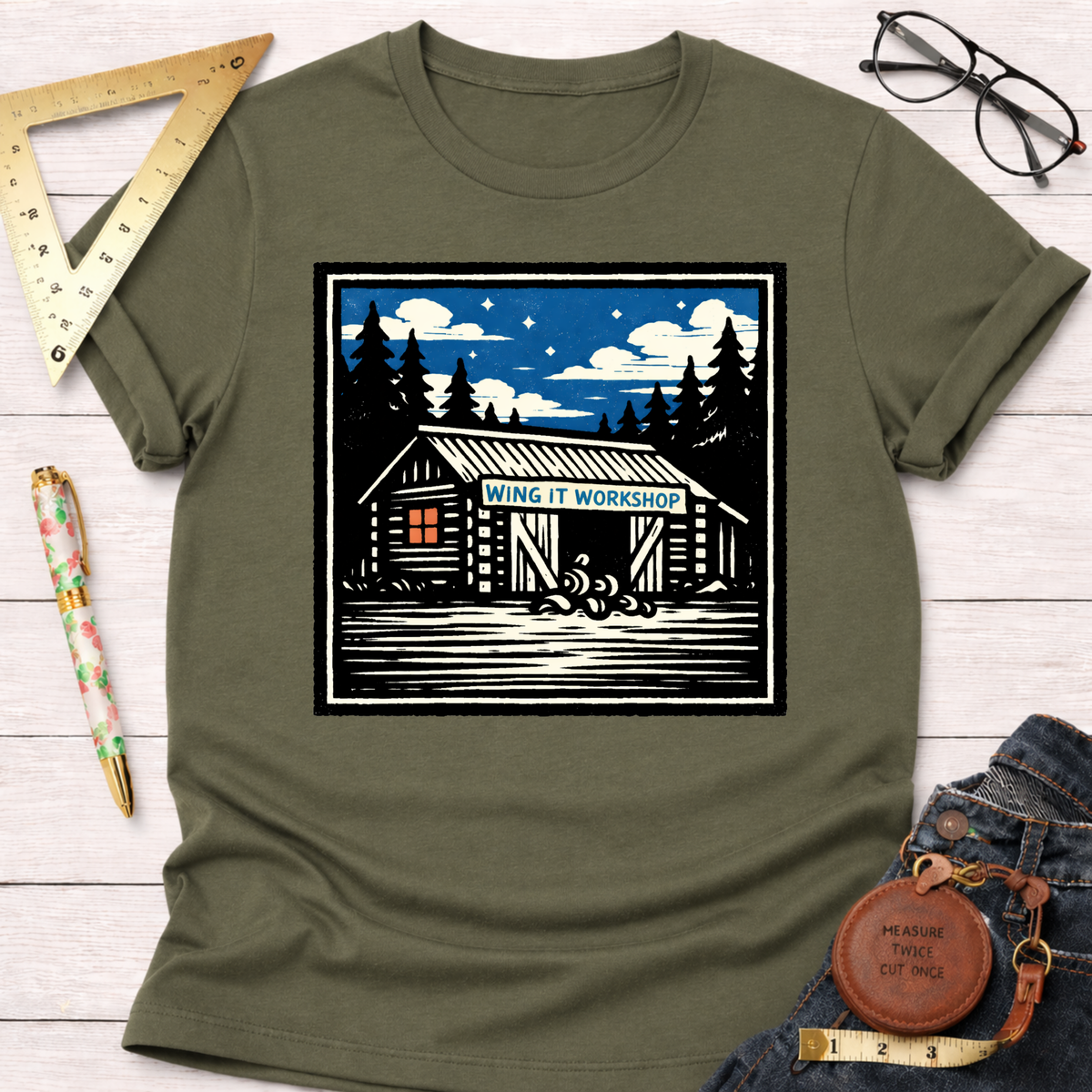 Olive green "Wing It Workshop" graphic tee with a cabin design under a starry night sky.