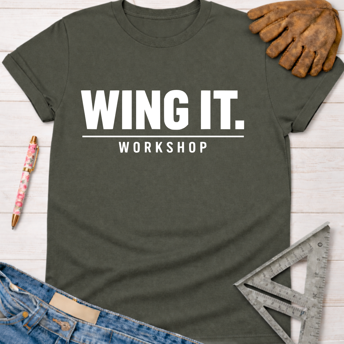 Women's funny woodworking graphic tee shirt for female woodworkers, makers, and DIY builders — Sawdust & Ponytails. Dark gray cotton tee with "WING IT. WORKSHOP" in white.