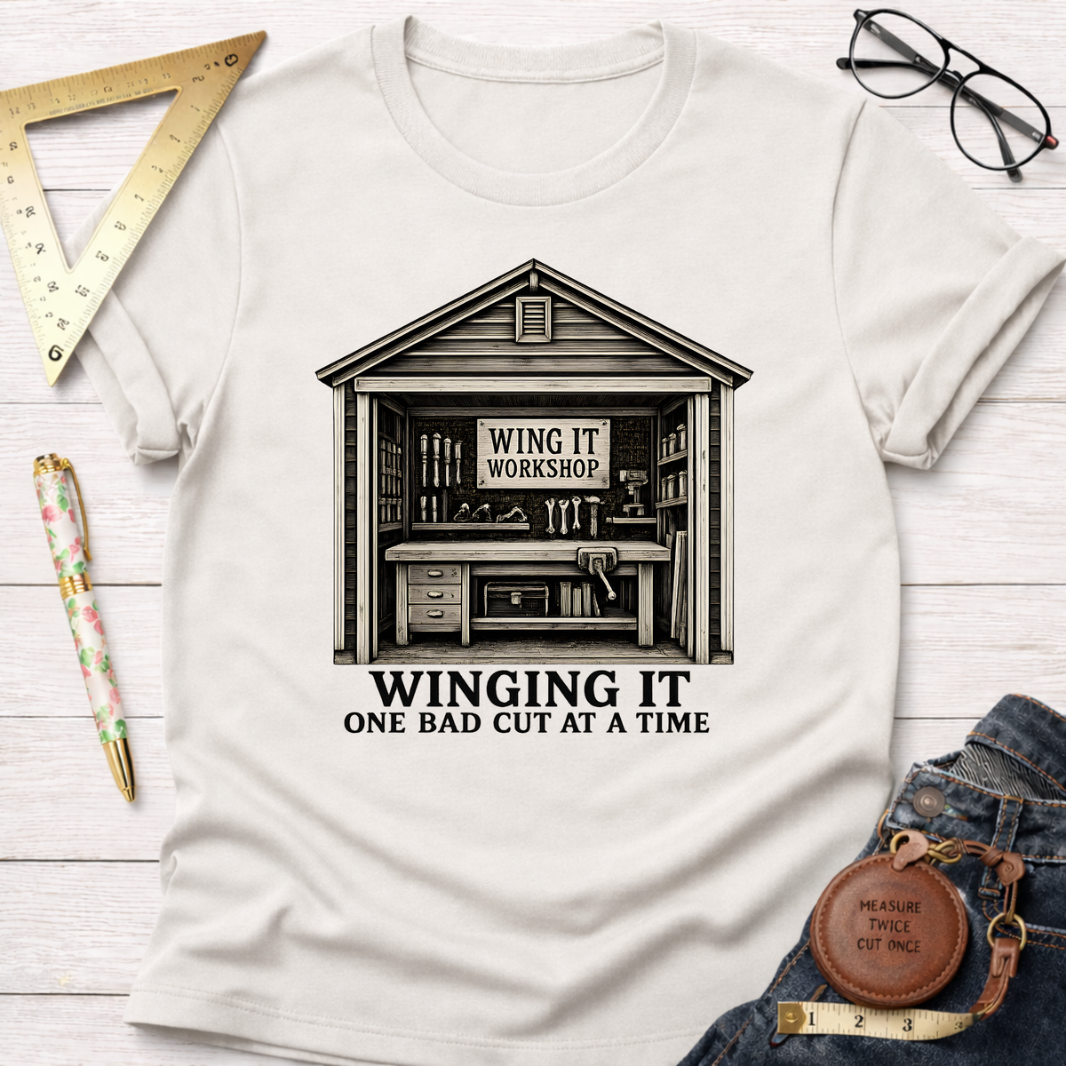 White t-shirt with "Winging It Workshop" shed graphic and "Winging It One Bad Cut At A Time" text.