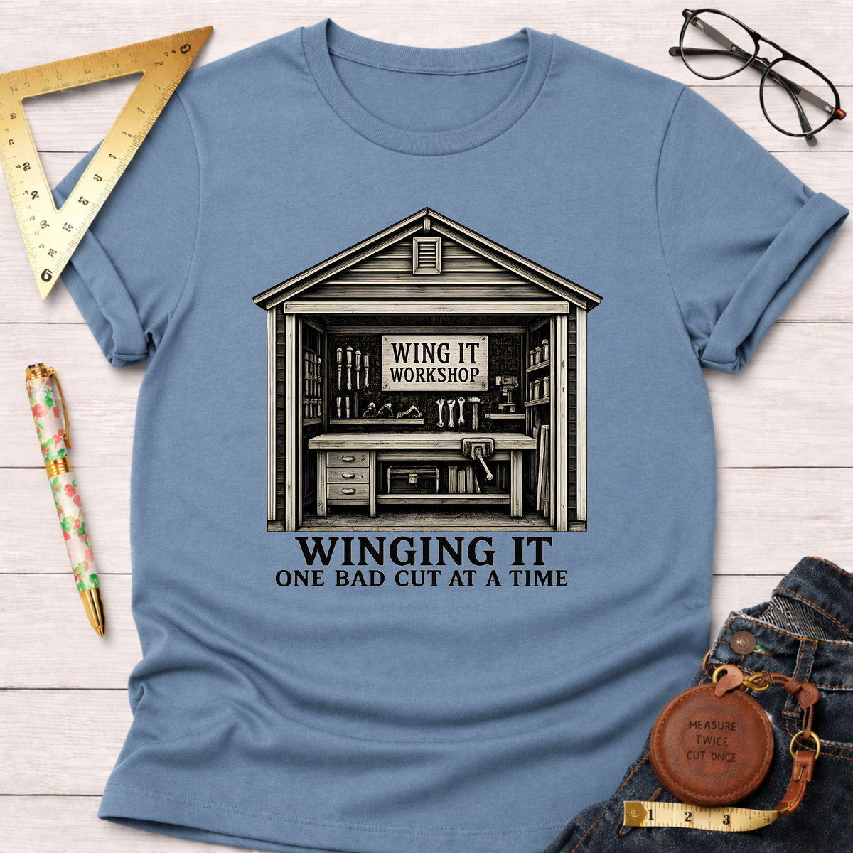 Light blue cotton t-shirt with a "Winging It Workshop" graphic and "One Bad Cut At A Time" text.