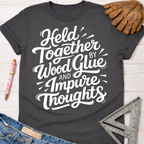 Dark gray women's "Held Together by Wood Glue and Impure Thoughts" graphic tee with work glove, pen, and ruler.