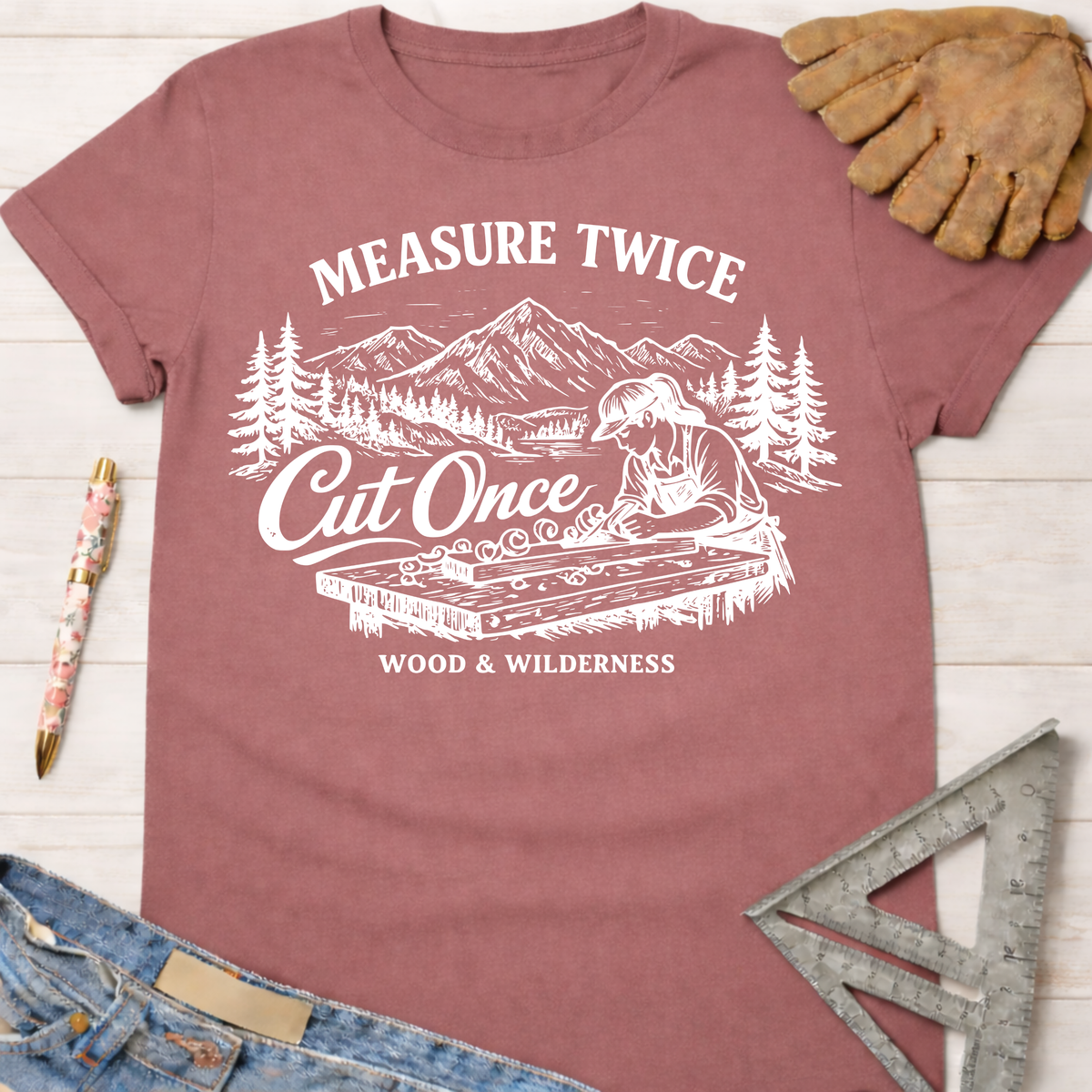 Women's funny woodworking graphic tee shirt for female woodworkers, makers, and DIY builders — Sawdust & Ponytails. Mauve cotton tee with "Measure Twice Cut Once" graphic.