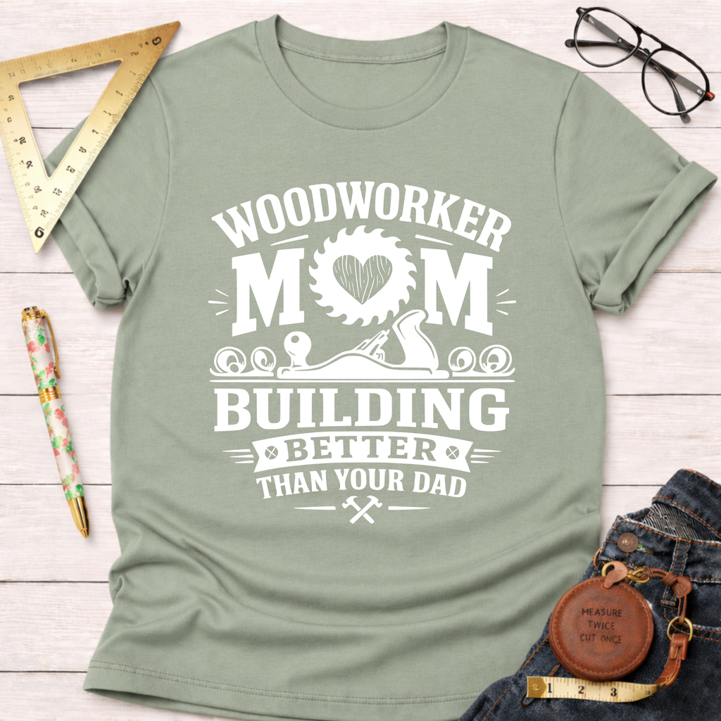 Women's funny woodworking graphic tee shirt for female woodworkers, makers, and DIY builders — Sawdust & Ponytails. Sage green crew neck t-shirt with "Woodworker Mom Building Better Than Your Dad" graphic.
