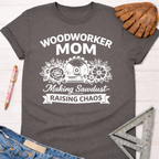 Charcoal gray Woodworker Mom t-shirt with white graphic of a saw blade, flowers, and "Making Sawdust Raising Chaos" text.
