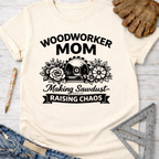 Women's funny woodworking graphic tee shirt for female woodworkers, makers, and DIY builders — Sawdust & Ponytails. Cream t-shirt with "Woodworker Mom Making Sawdust Raising Chaos" graphic.