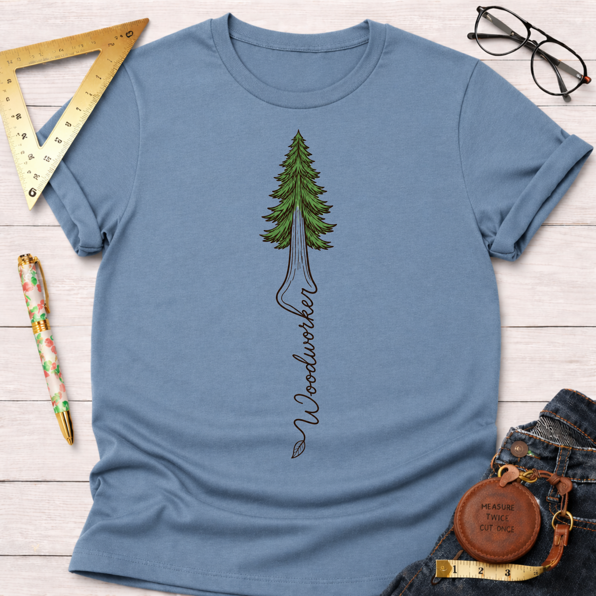 Women's funny woodworking graphic tee shirt for female woodworkers, makers, and DIY builders — Sawdust & Ponytails. Blue crewneck t-shirt with a green redwood tree graphic and "Woodworker" text.