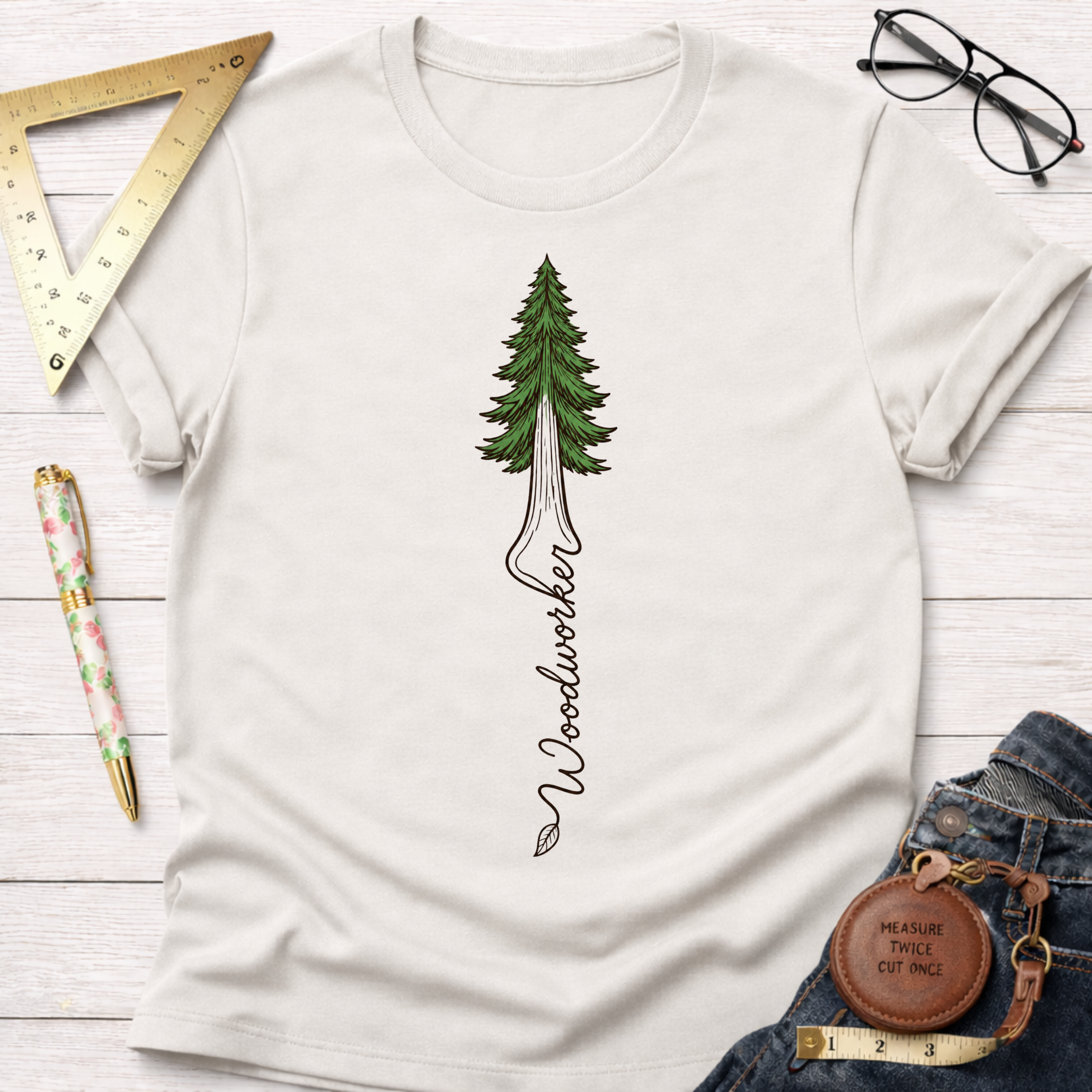 Women's funny woodworking graphic tee shirt for female woodworkers, makers, and DIY builders — Sawdust & Ponytails. Cream cotton tee with a green redwood tree graphic and "Woodworker" text.