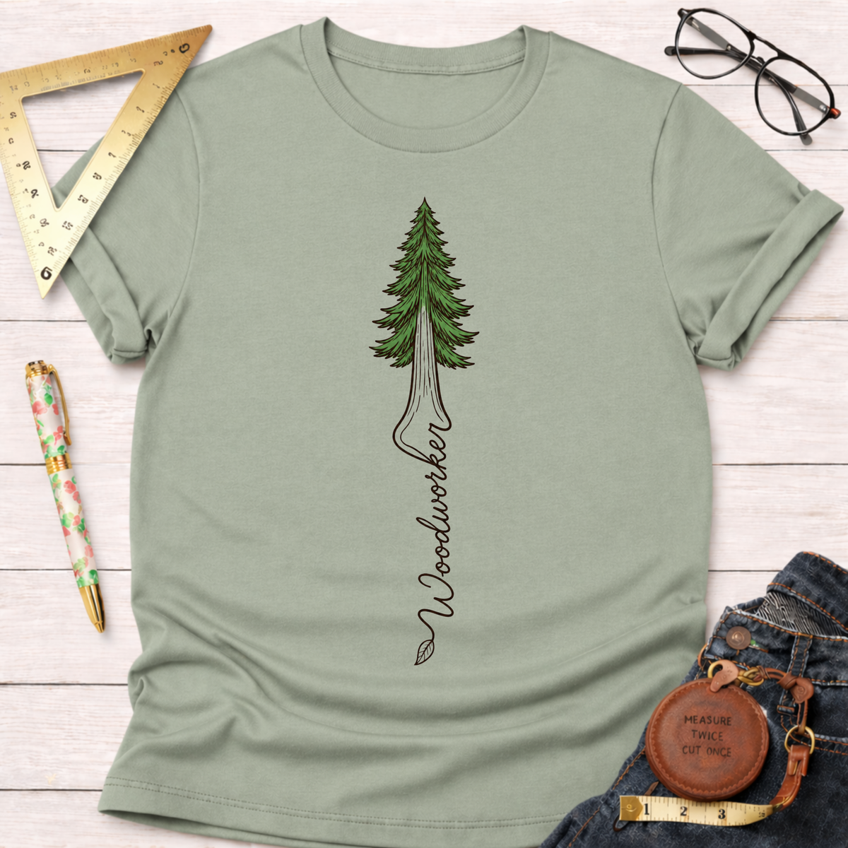 Women's funny woodworking graphic tee shirt for female woodworkers, makers, and DIY builders — Sawdust & Ponytails. Sage green crewneck t-shirt with a redwood tree and "Woodworker" text.