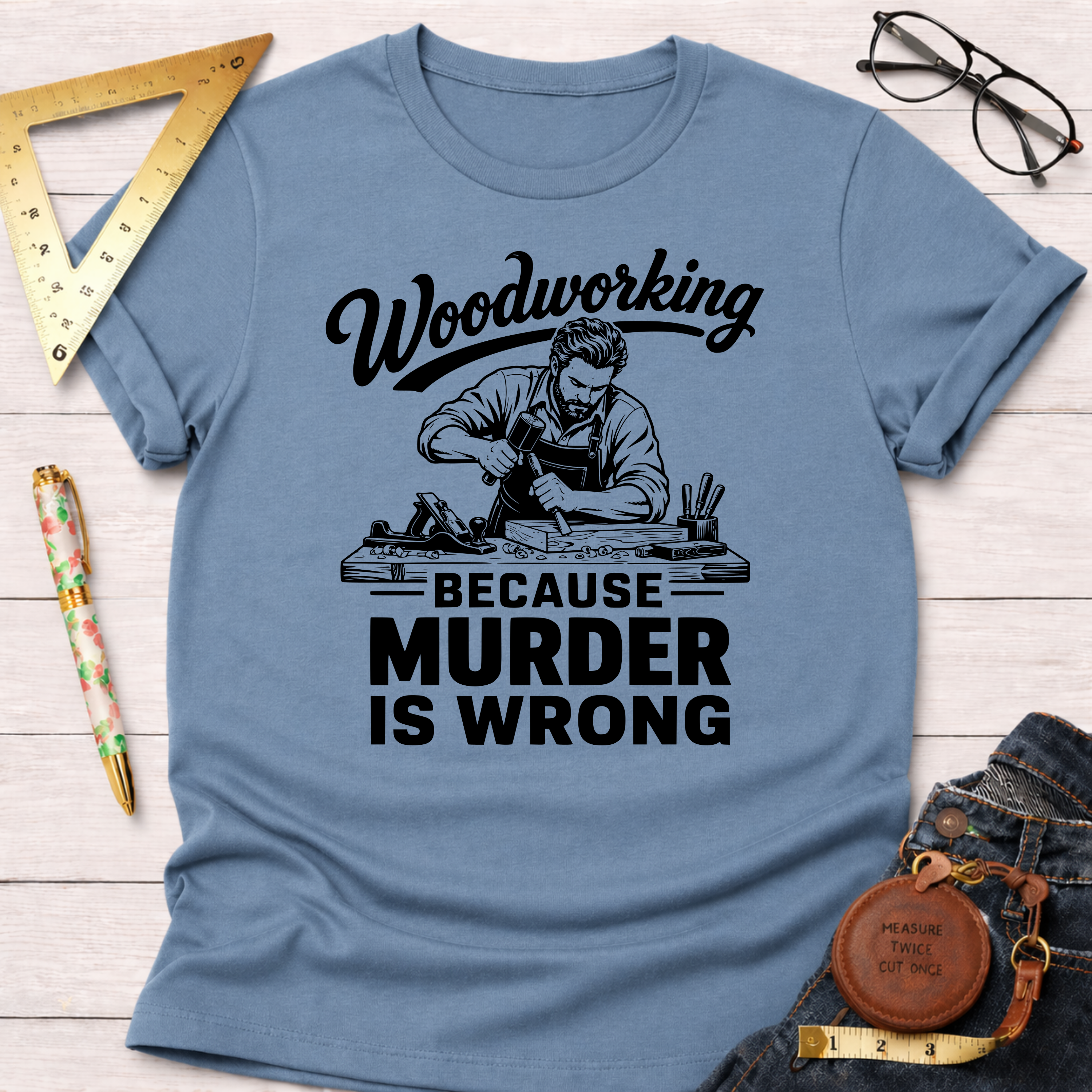 Light blue "Woodworking Because Murder Is Wrong" t-shirt with a graphic of a man woodworking.