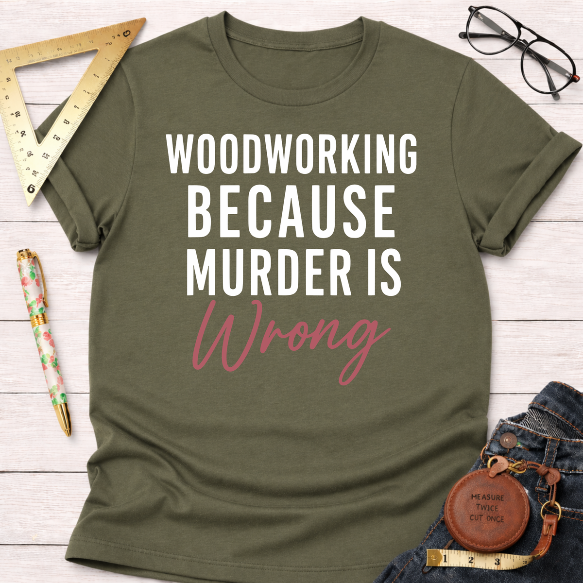 Olive green t-shirt with "WOODWORKING BECAUSE MURDER IS Wrong" in white and pink text.