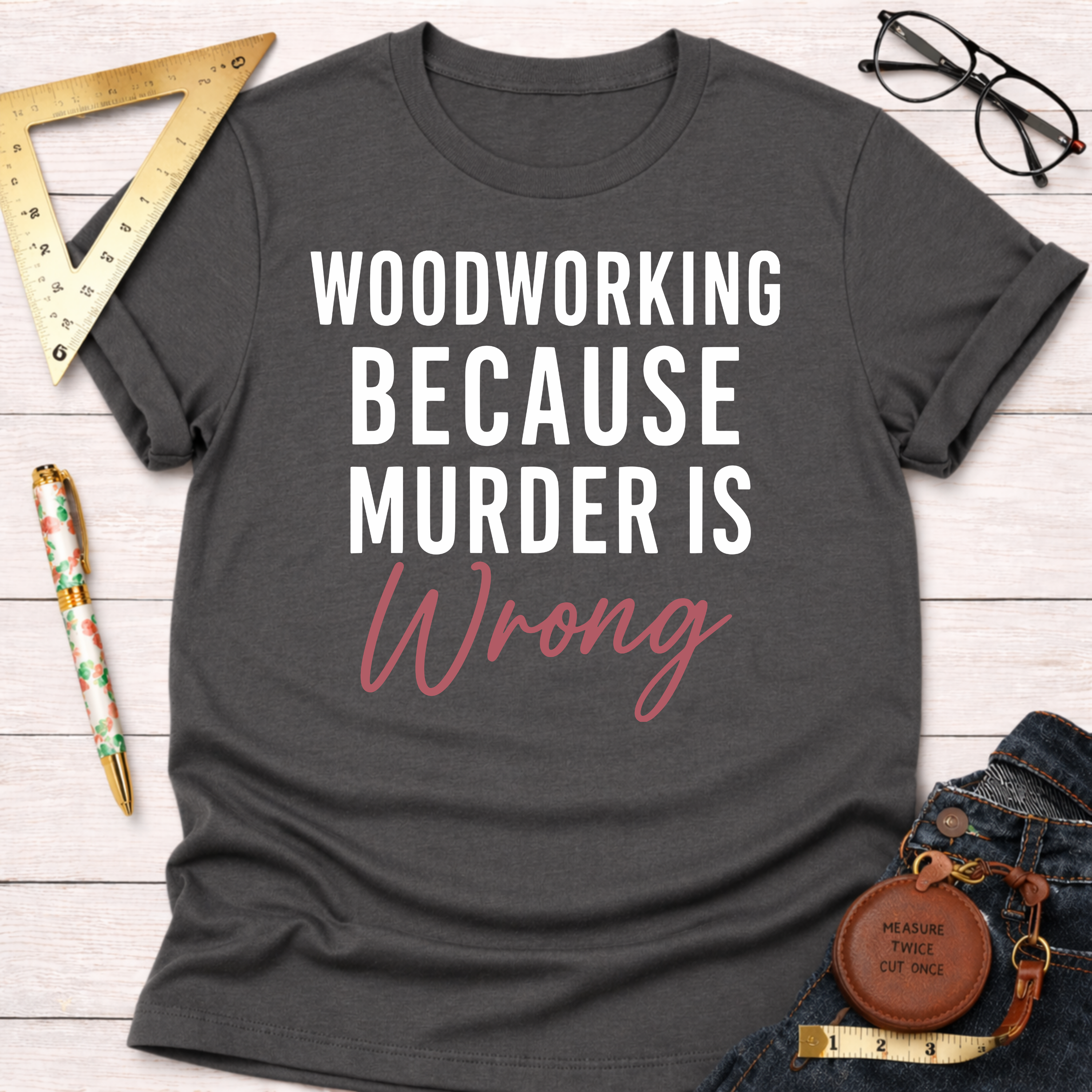 Dark gray t-shirt with "WOODWORKING BECAUSE MURDER IS Wrong" in white and pink script.
