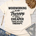 Women's funny woodworking graphic tee shirt for female woodworkers, makers, and DIY builders — Sawdust & Ponytails. Cream t-shirt with "Woodworking Is My Therapy Still Cheaper Than Actual Therapy" in black text.