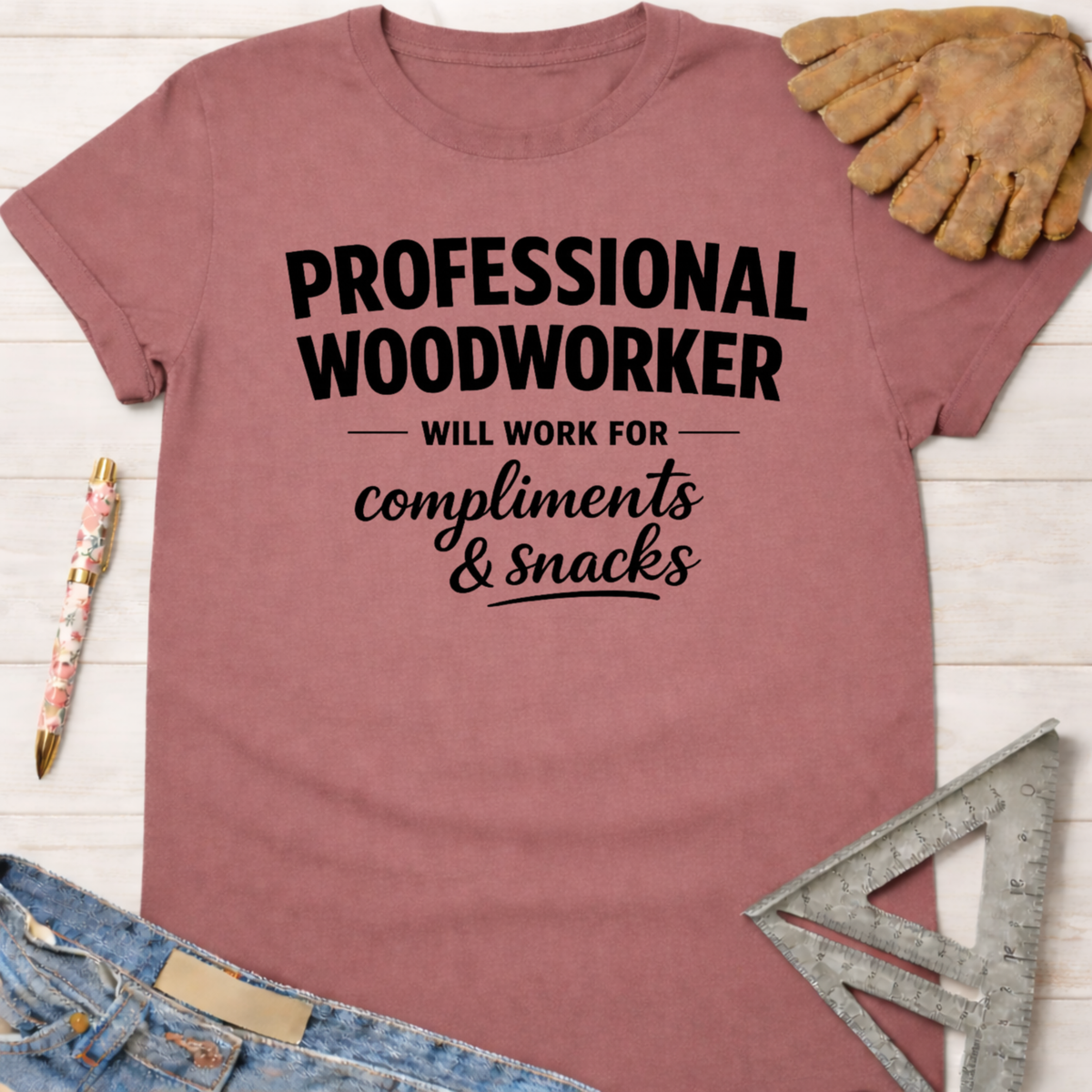 Women's funny woodworking graphic tee shirt for female woodworkers, makers, and DIY builders — Sawdust & Ponytails. Mauve cotton tee with "Professional Woodworker Will Work For Compliments & Snacks" in black text.