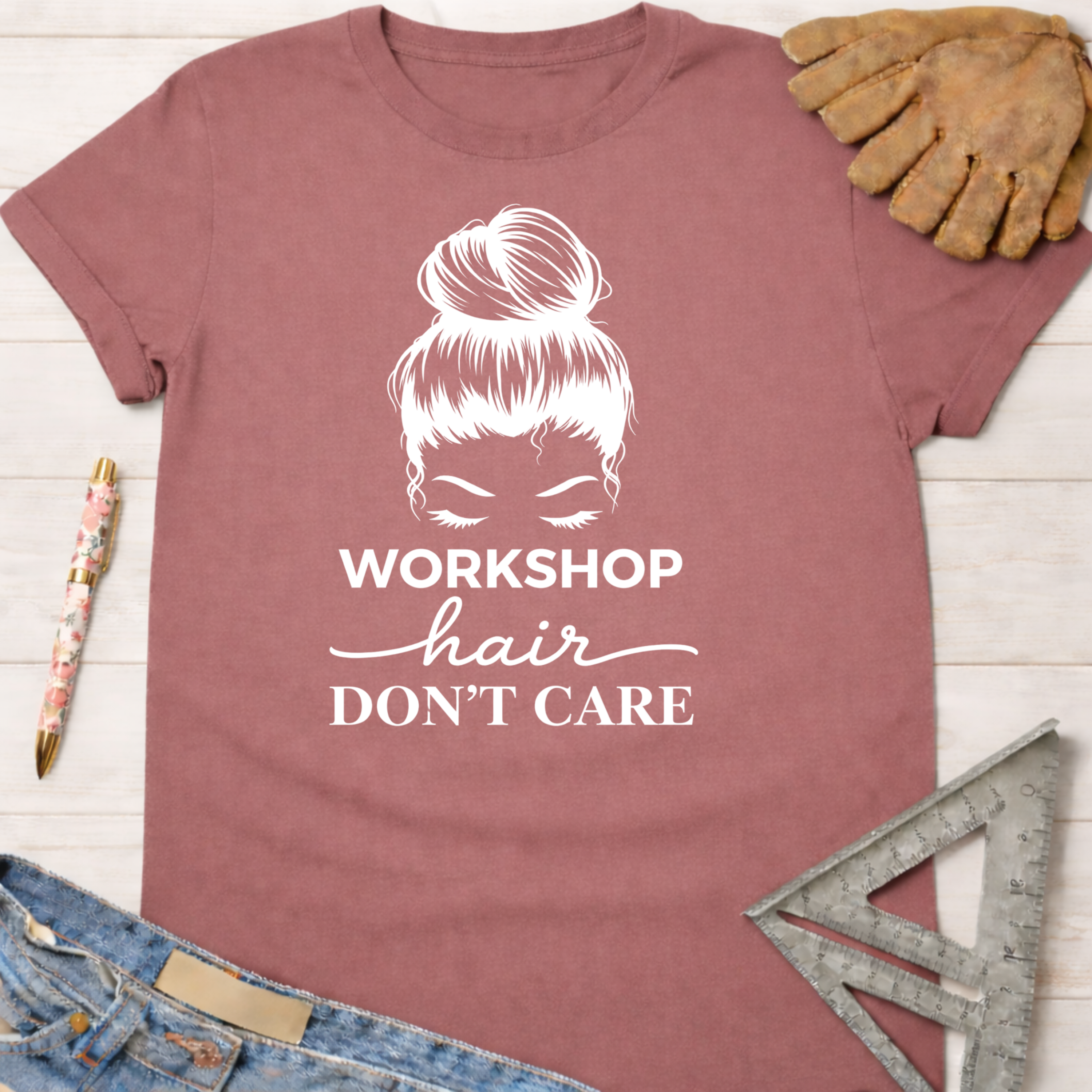 Women's funny woodworking graphic tee shirt for female woodworkers, makers, and DIY builders — Sawdust & Ponytails. Mauve cotton tee with "Workshop Hair Don't Care" and messy bun graphic.