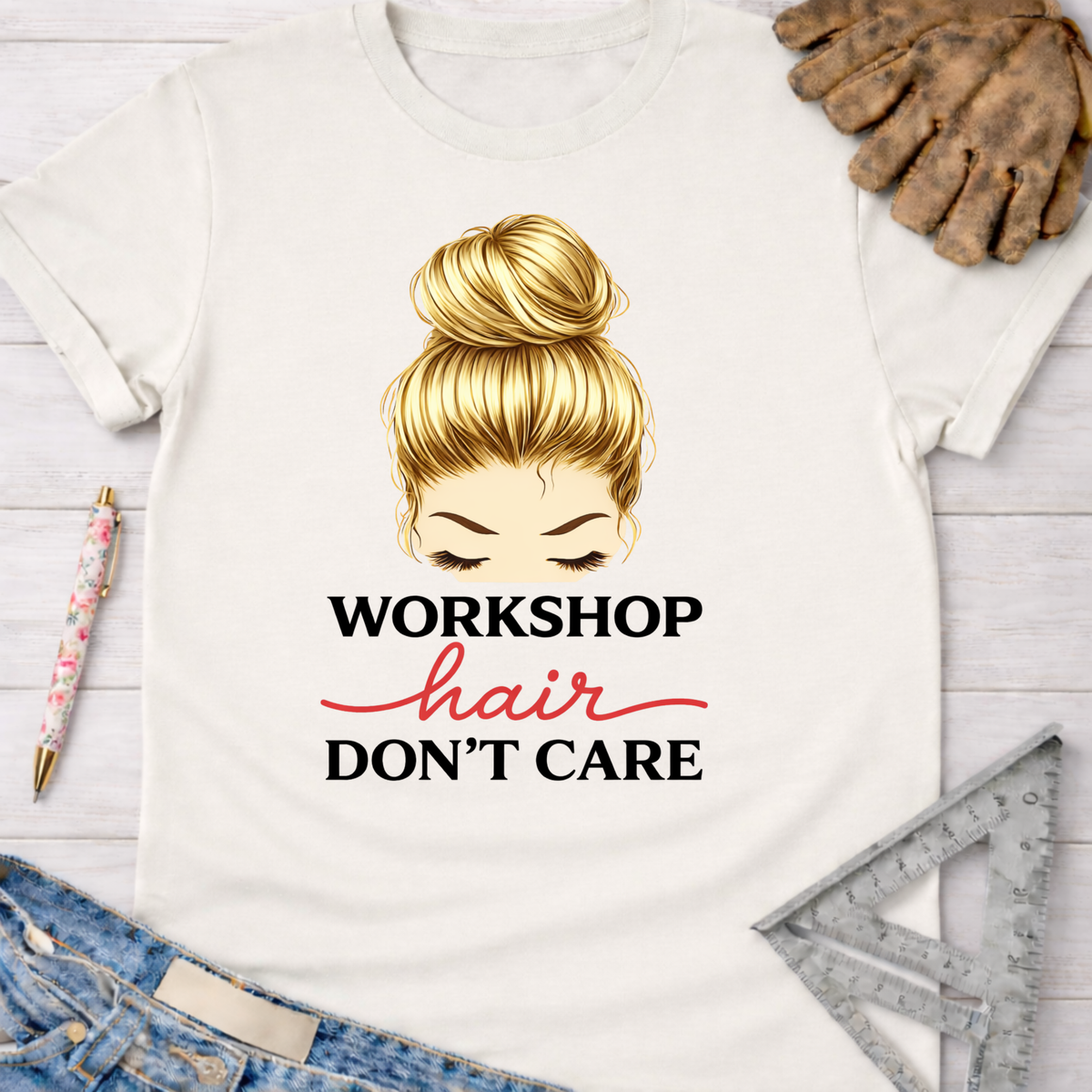 Women's funny woodworking graphic tee shirt for female woodworkers, makers, and DIY builders — Sawdust & Ponytails. White cotton t-shirt with "Workshop Hair Don't Care" text and a blonde messy bun illustration.