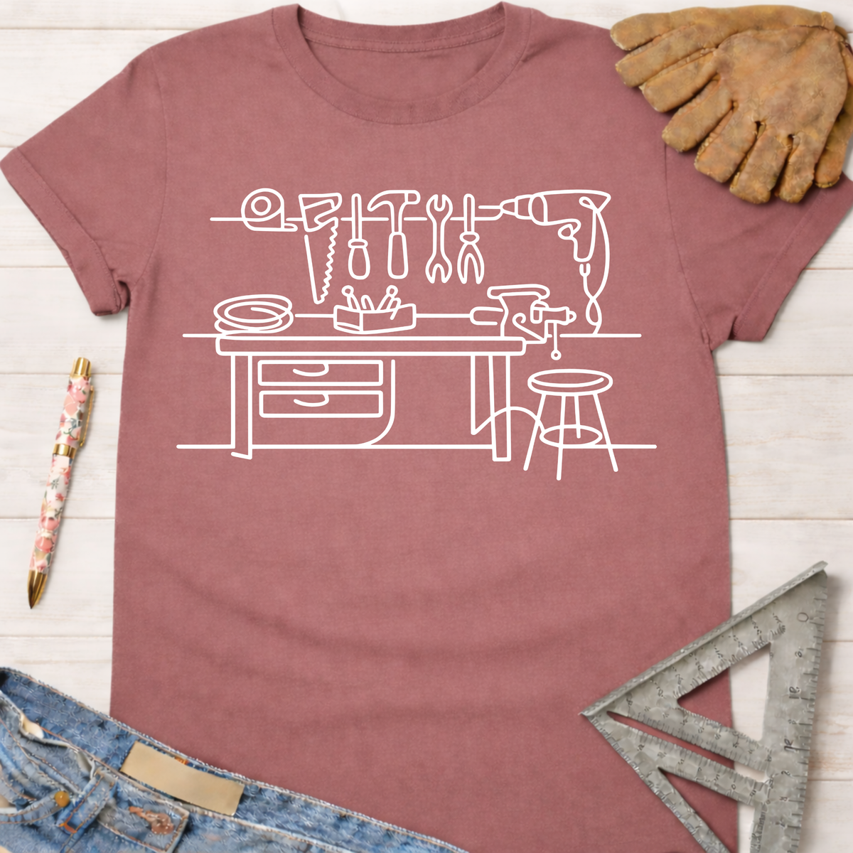 Women's funny woodworking graphic tee shirt for female woodworkers, makers, and DIY builders — Sawdust & Ponytails. Mauve cotton tee with white line art workshop tools.