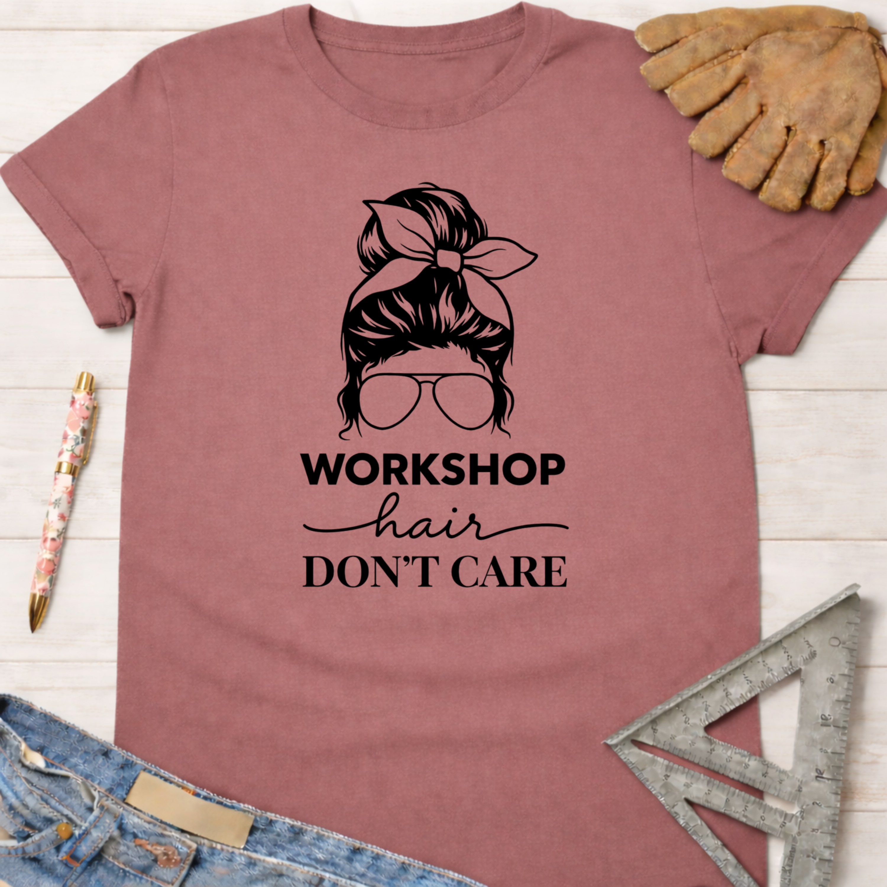 Women's funny woodworking graphic tee shirt for female woodworkers, makers, and DIY builders — Sawdust & Ponytails. Mauve cotton tee with "Workshop Hair Don't Care" messy bun graphic.