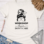 Women's funny woodworking graphic tee shirt for female woodworkers, makers, and DIY builders — Sawdust & Ponytails. Cream t-shirt with "Workshop Hair Don't Care" messy bun graphic.