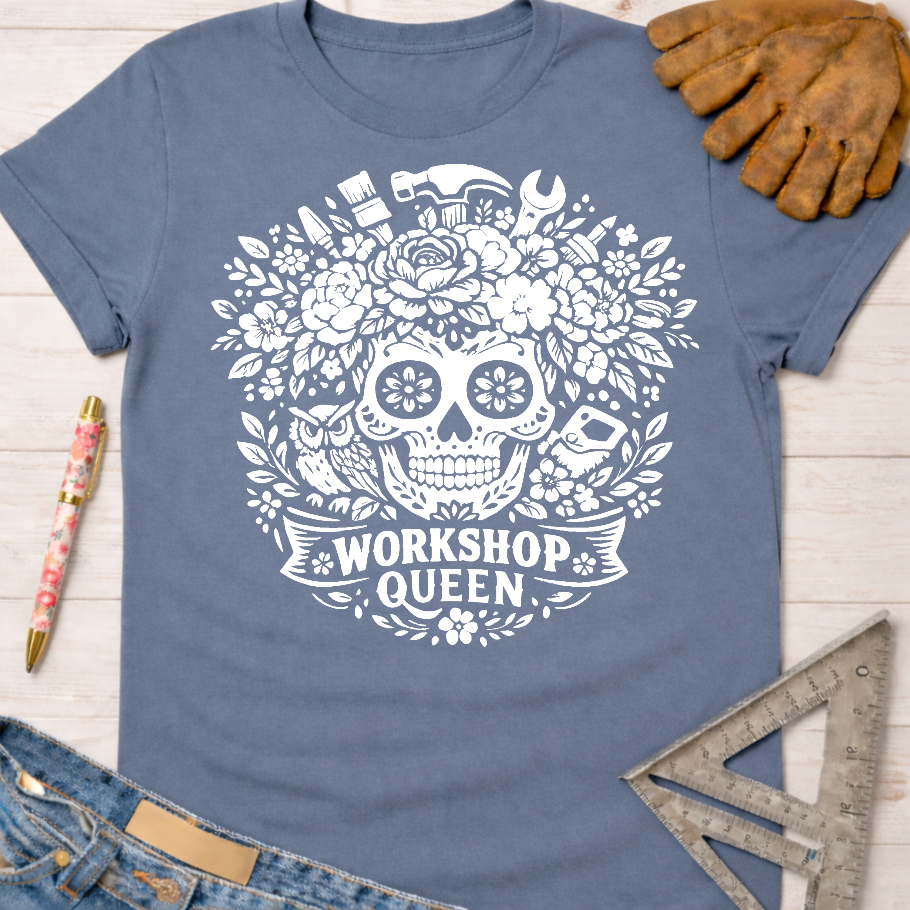 Dusty blue t-shirt with white floral skull, tools, and "Workshop Queen" graphic. Women's funny woodworking graphic tee shirt for female woodworkers, makers, and DIY builders — Sawdust & Ponytails