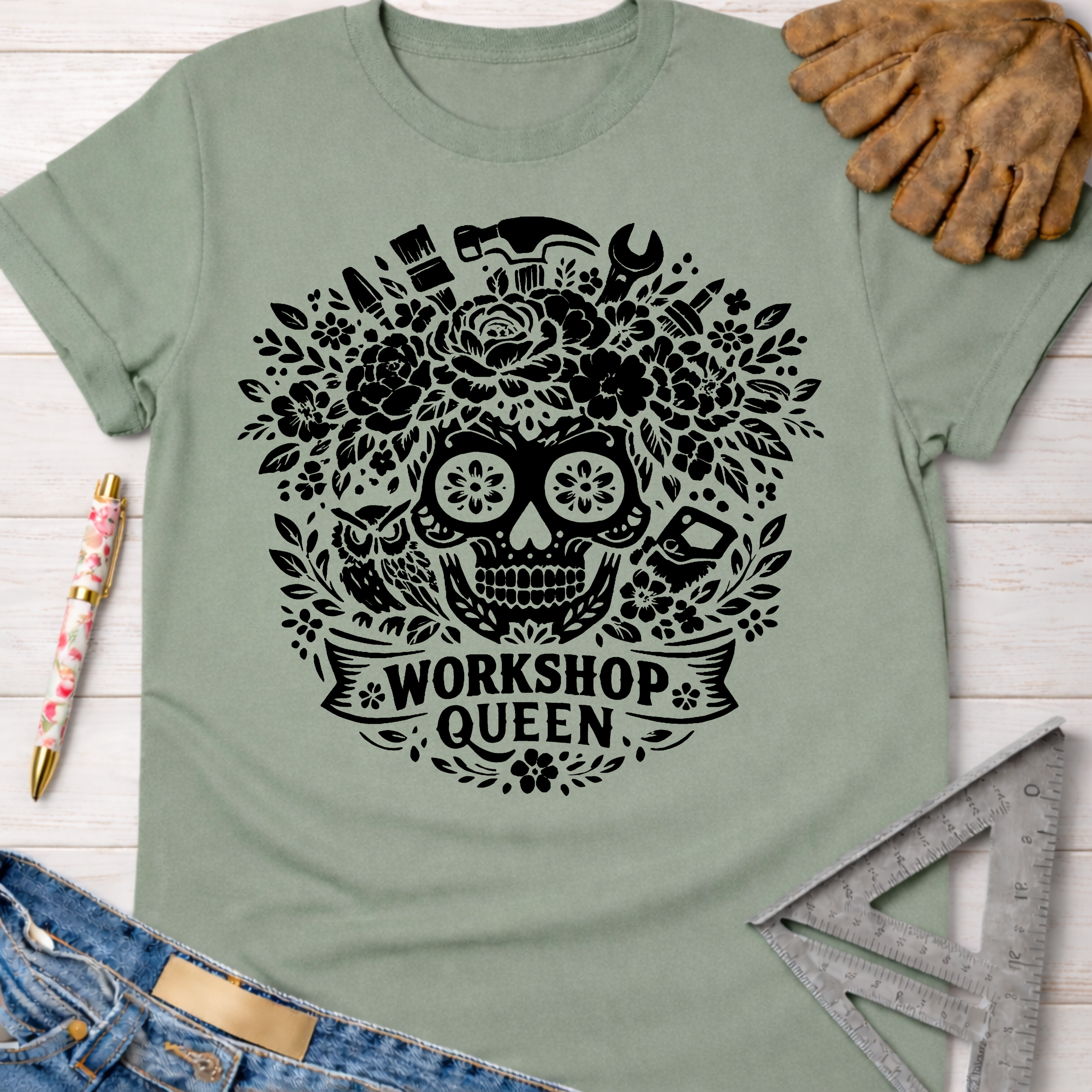 Sage green women's funny woodworking graphic tee shirt for female woodworkers, makers, and DIY builders — Sawdust & Ponytails, featuring a black floral skull and tools design with "Workshop Queen" text.