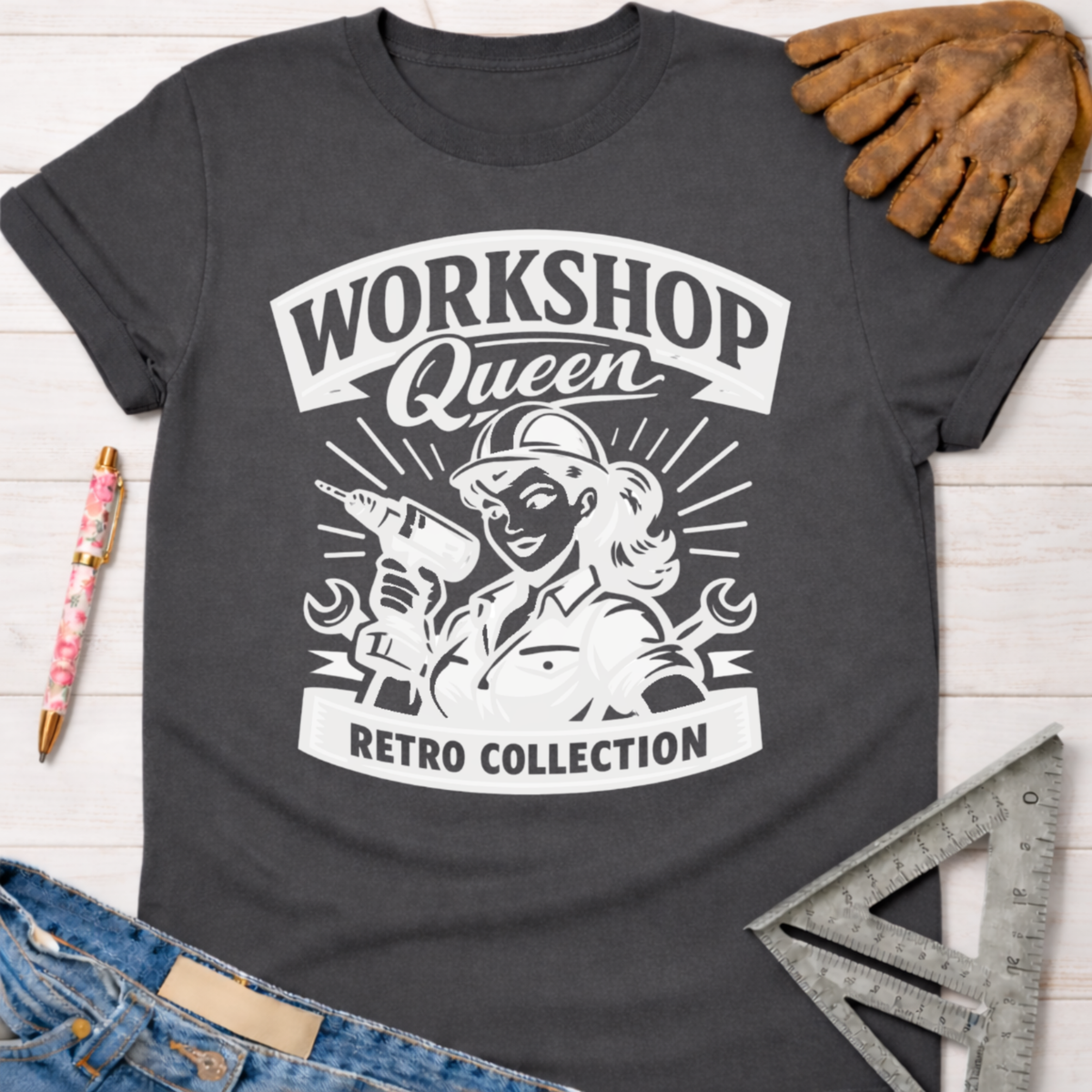 Charcoal gray cotton "Workshop Queen Retro Collection" graphic tee with a female builder holding a drill, next to work gloves and jeans. Women's funny woodworking graphic tee shirt for female woodworkers, makers, and DIY builders — Sawdust & Ponytails