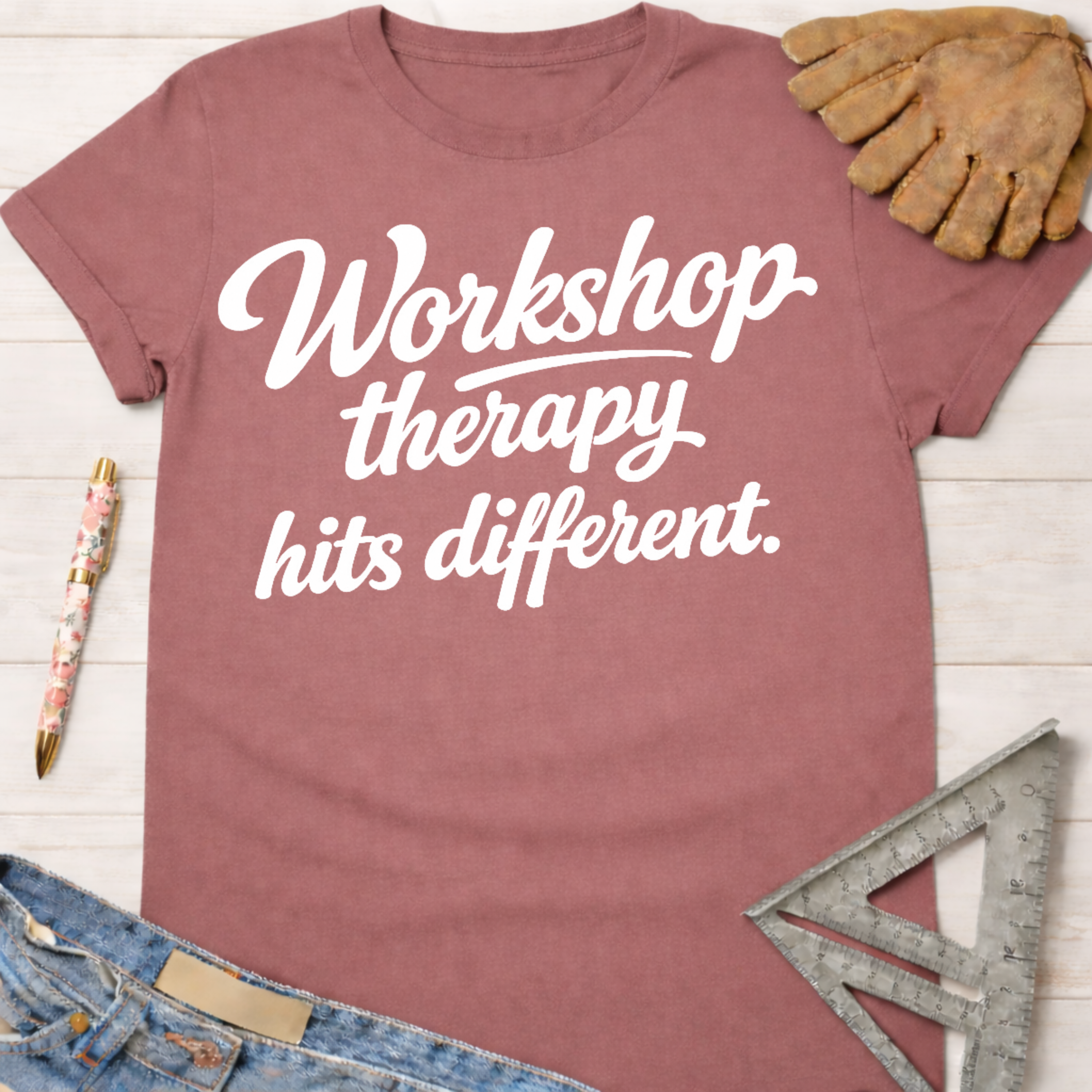 Women's funny woodworking graphic tee shirt for female woodworkers, makers, and DIY builders — Sawdust & Ponytails. Mauve t-shirt with "Workshop therapy hits different" in white script.
