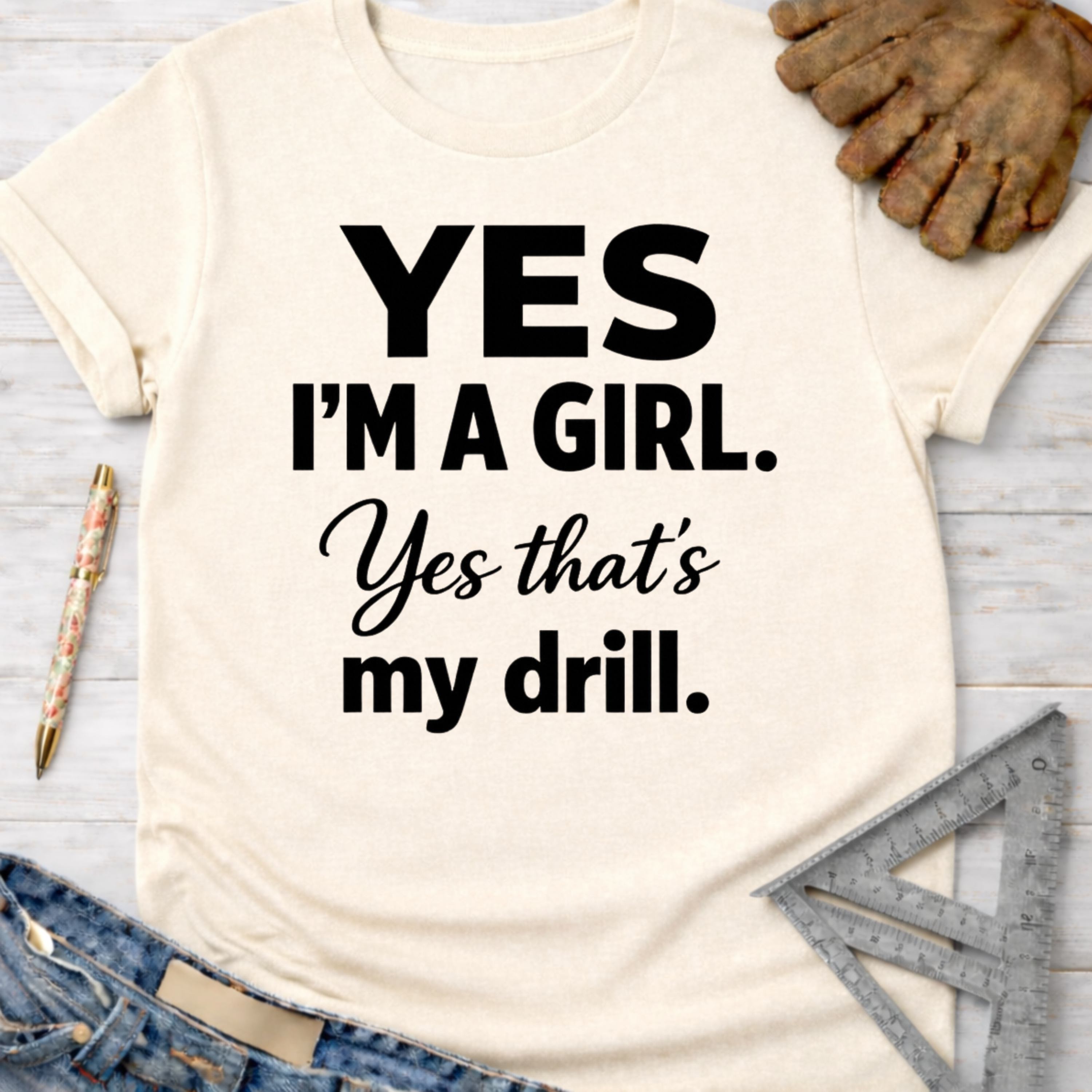 Women's funny woodworking graphic tee shirt for female woodworkers, makers, and DIY builders — Sawdust & Ponytails. Cream t-shirt with "YES I'M A GIRL. Yes that's my drill." in black text.