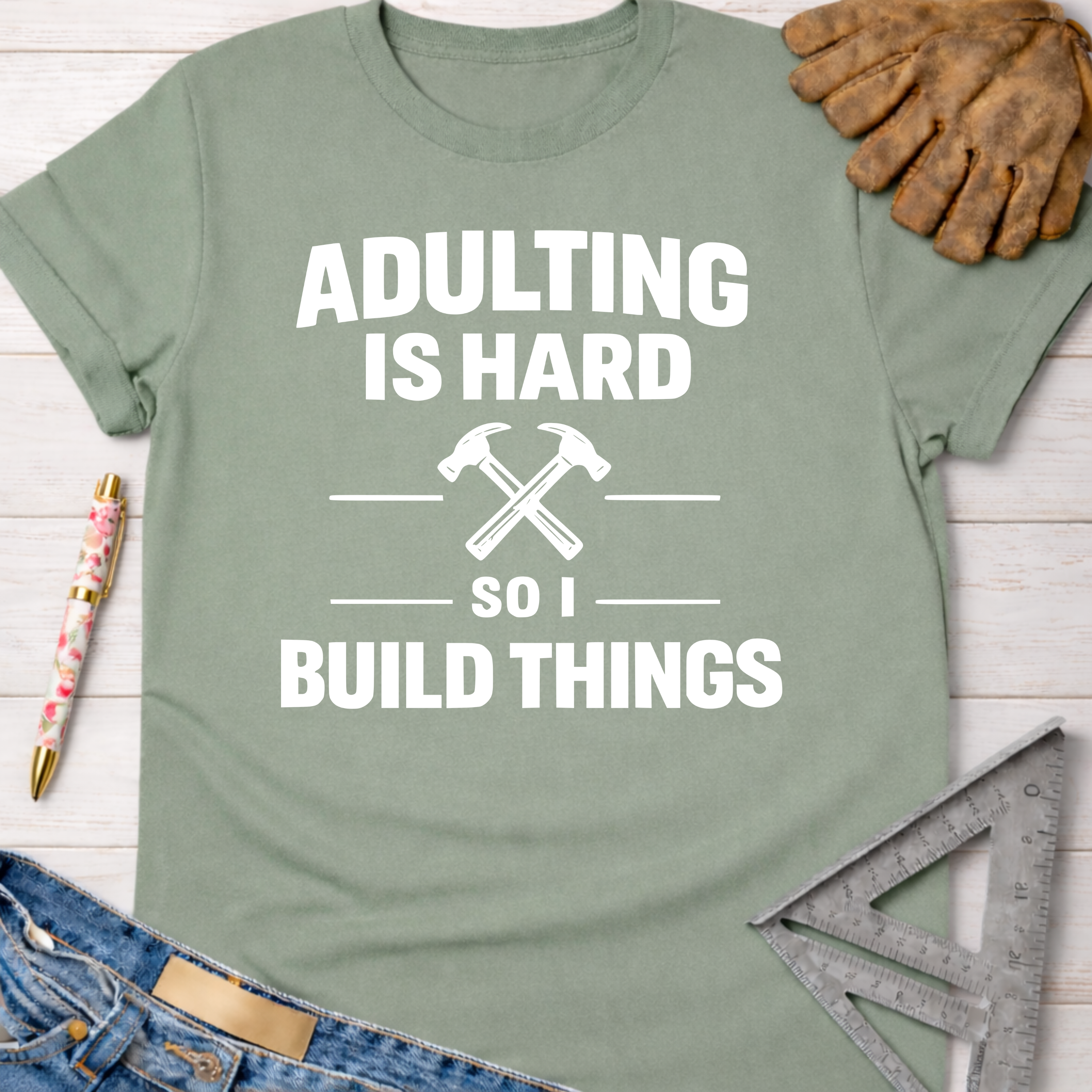 Sage green "Adulting Is Hard So I Build Things" tee with crossed hammers, for female woodworkers.