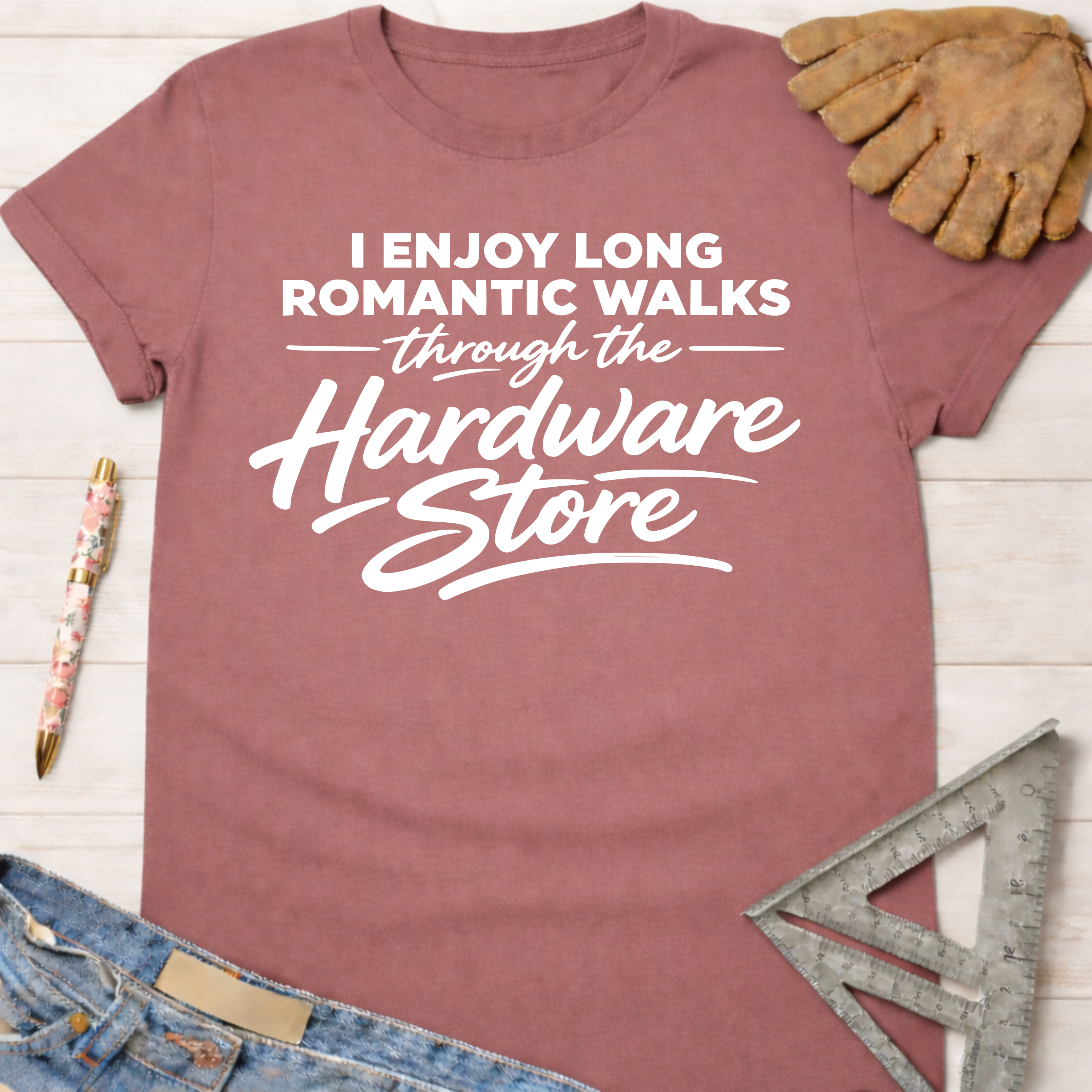 Women's funny woodworking graphic tee shirt for female woodworkers, makers, and DIY builders — Sawdust & Ponytails. Mauve cotton tee with "I Enjoy Long Romantic Walks Through The Hardware Store" in white text.