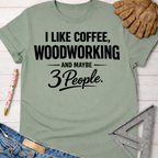 Women's funny woodworking graphic tee shirt for female woodworkers, makers, and DIY builders — Sawdust & Ponytails. Sage green cotton tee with "I LIKE COFFEE, WOODWORKING AND MAYBE 3 PEOPLE" in black text, styled with jeans, a pen, work glove, and ruler.