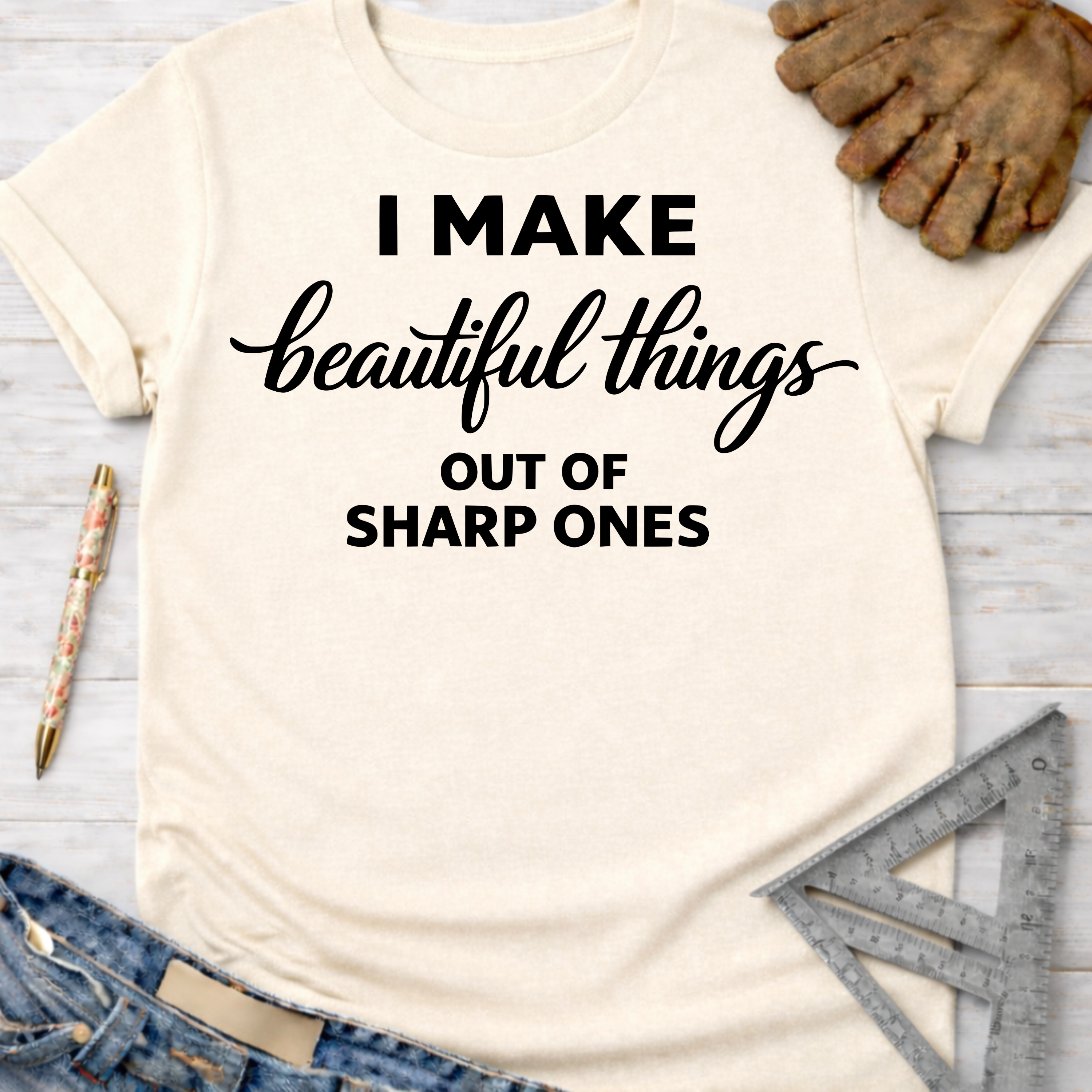 Women's funny woodworking graphic tee shirt for female woodworkers, makers, and DIY builders — Sawdust & Ponytails. Cream t-shirt with "I MAKE beautiful things OUT OF SHARP ONES" in black text.
