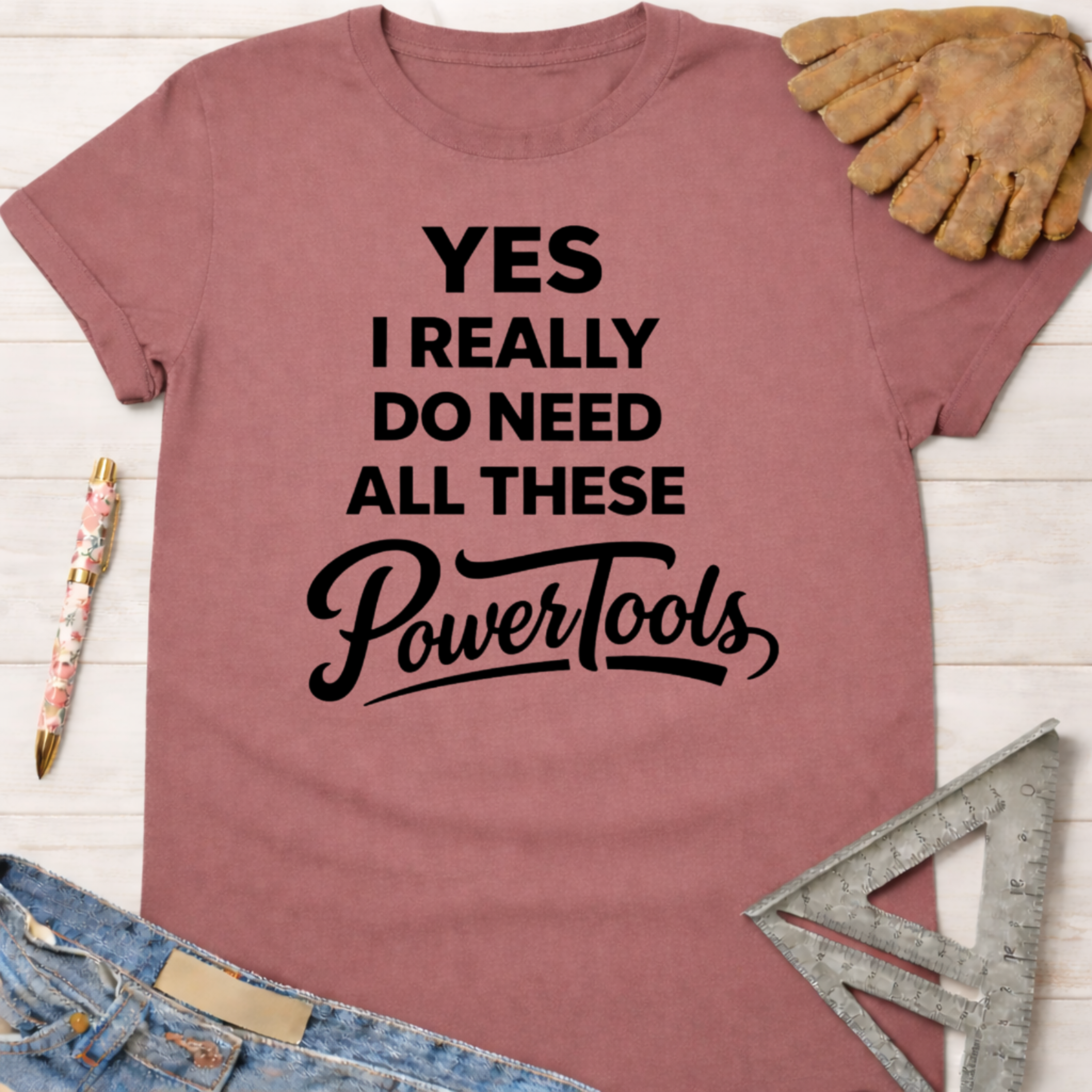 Women's funny woodworking graphic tee shirt for female woodworkers, makers, and DIY builders — Sawdust & Ponytails. Mauve t-shirt with "YES I REALLY DO NEED ALL THESE PowerTools" in black text.