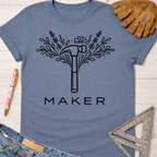 Women's funny woodworking graphic tee shirt for female woodworkers, makers, and DIY builders — Sawdust & Ponytails. Blue cotton tee with a black floral hammer graphic and "MAKER" text.
