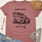 Women's funny woodworking graphic tee shirt for female woodworkers, makers, and DIY builders — Sawdust & Ponytails. Mauve cotton tee with "SAFETY FIRST. obviously" text and a frog wearing safety glasses.
