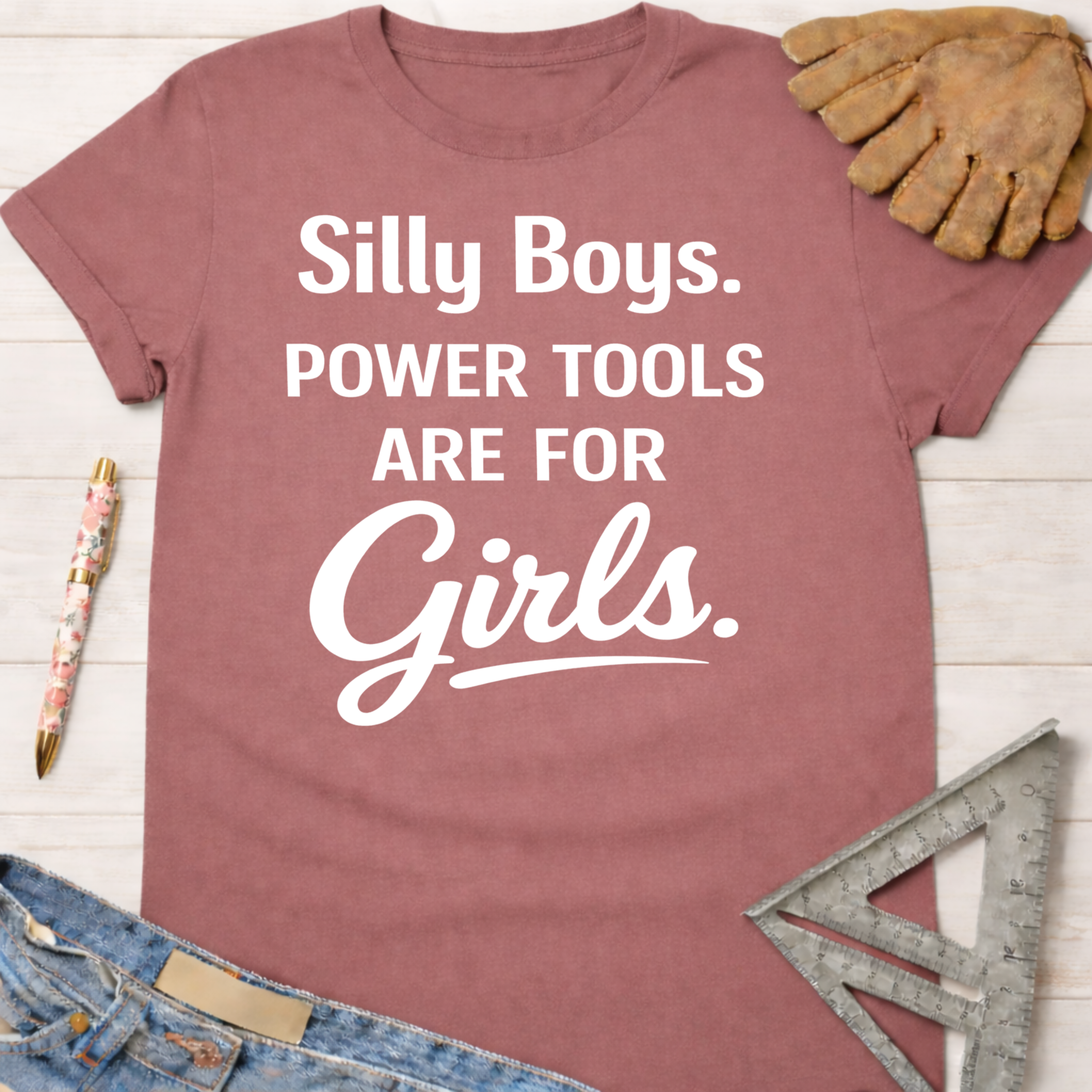 Women's funny woodworking graphic tee shirt for female woodworkers, makers, and DIY builders — Sawdust & Ponytails. Mauve cotton tee with "Silly Boys. Power Tools Are For Girls." in white text.