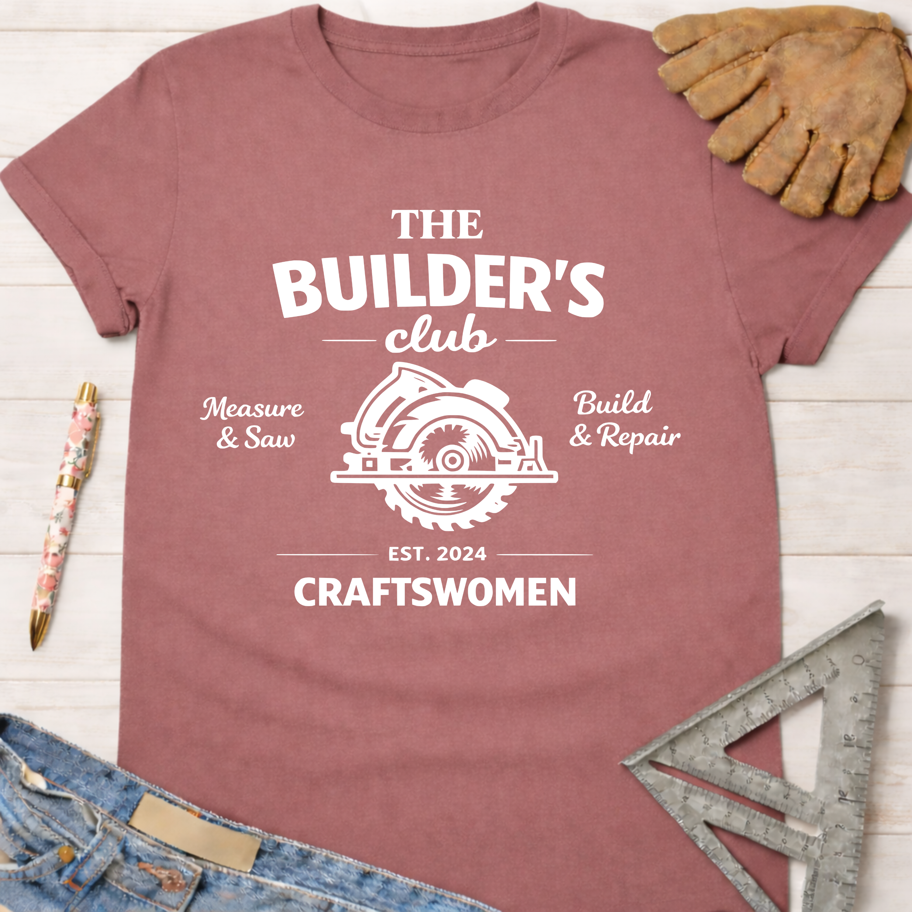 Women's funny woodworking graphic tee shirt for female woodworkers, makers, and DIY builders — Sawdust & Ponytails. Mauve cotton tee with "The Builder's Club" circular saw graphic.